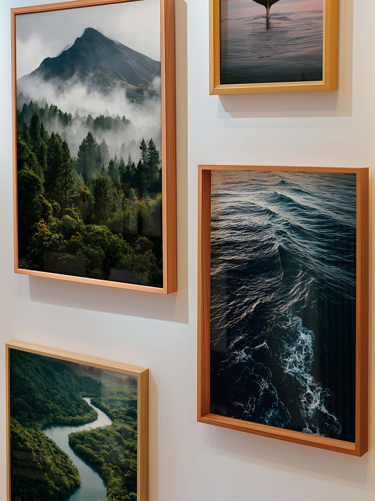 Vier gerahmte Naturfotografien mit Berglandschaft im Nebel, Flussverlauf und Meereswellen, arrangiert als moderne Bilderwand in einem hellen Wohnraum.