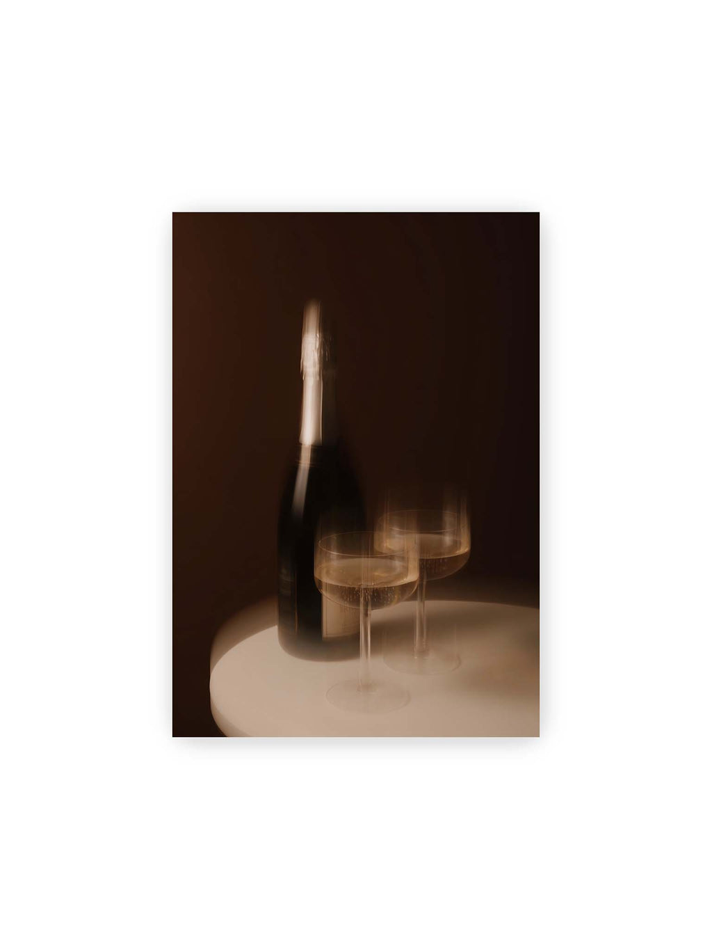 21x30 cm – Dunkle Flasche und zwei gefüllte Weingläser mit warmen Lichtreflexen auf einem runden hellen Tisch.