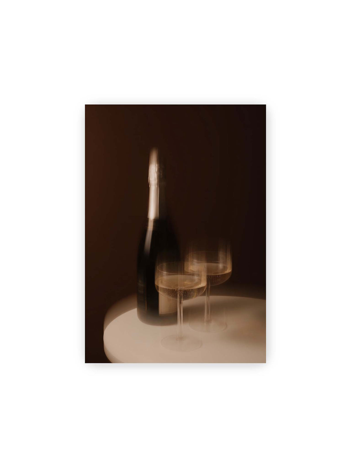 21x30 cm – Dunkle Flasche und zwei gefüllte Weingläser mit warmen Lichtreflexen auf einem runden hellen Tisch.