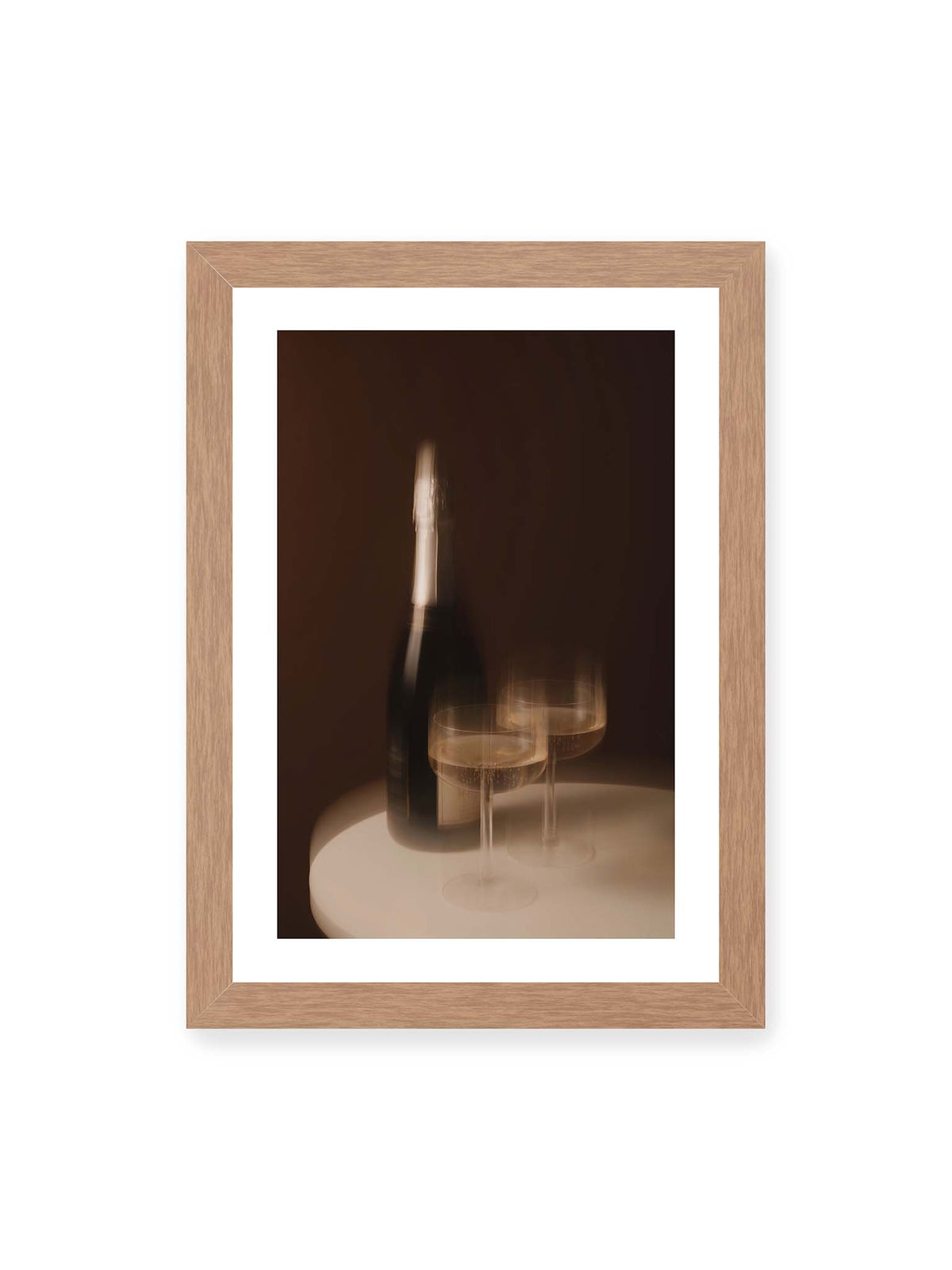 21x30 cm, weißer Galerie-Rand, Eichenrahmen – Dunkle Flasche und zwei gefüllte Weingläser mit warmen Lichtreflexen auf einem runden hellen Tisch.