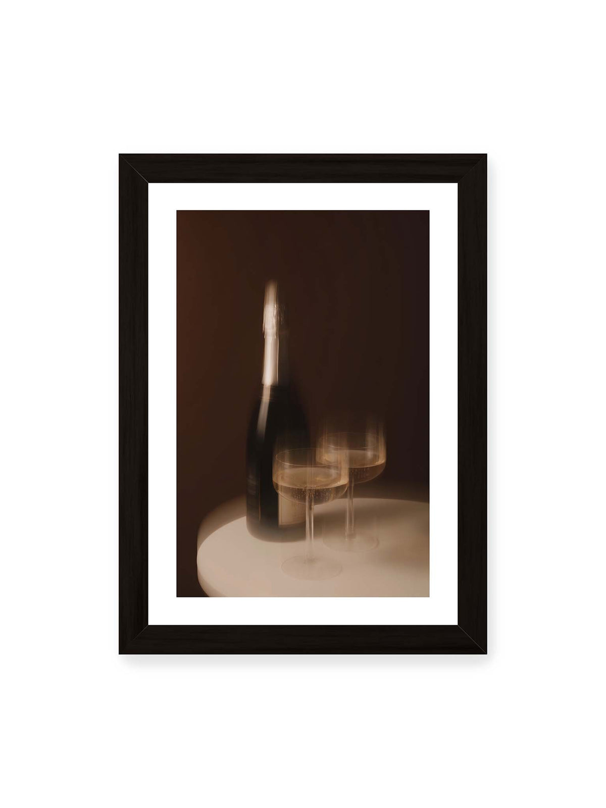 21x30 cm, weißer Galerie-Rand, schwarzer Rahmen – Dunkle Flasche und zwei gefüllte Weingläser mit warmen Lichtreflexen auf einem runden hellen Tisch.