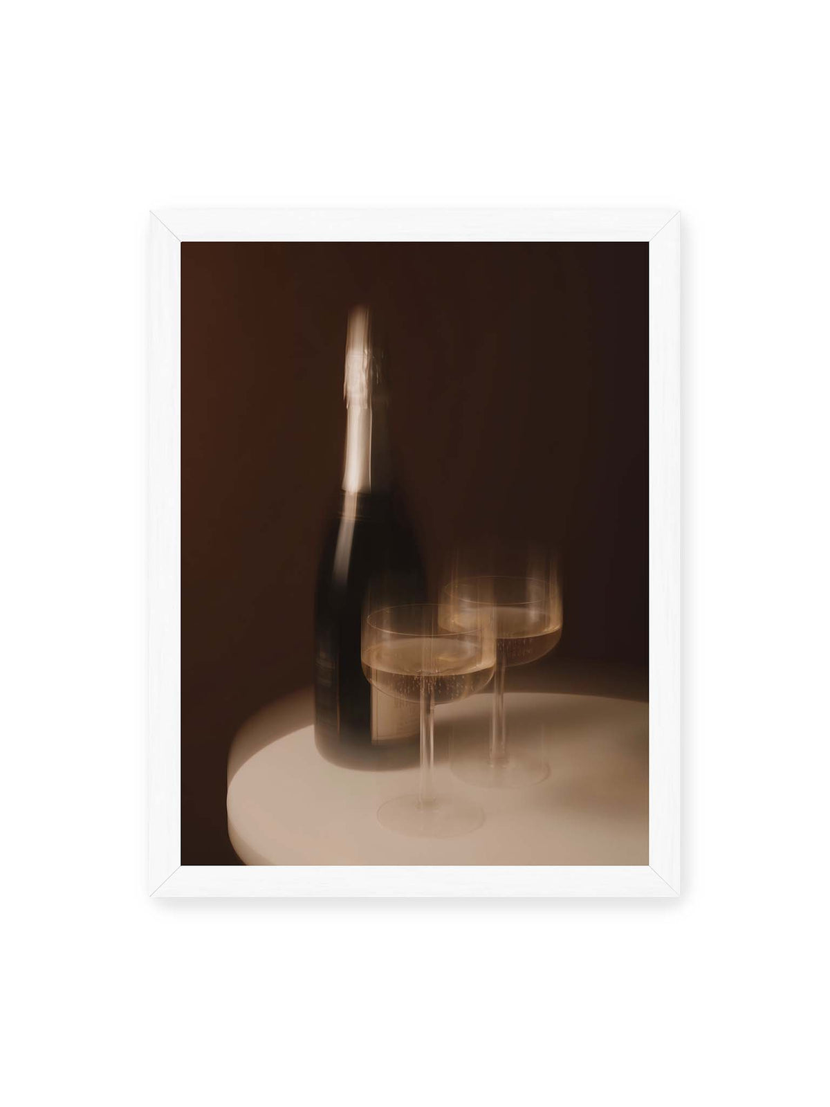 30x40 cm, weißer Rahmen – Dunkle Flasche und zwei gefüllte Weingläser mit warmen Lichtreflexen auf einem runden hellen Tisch.