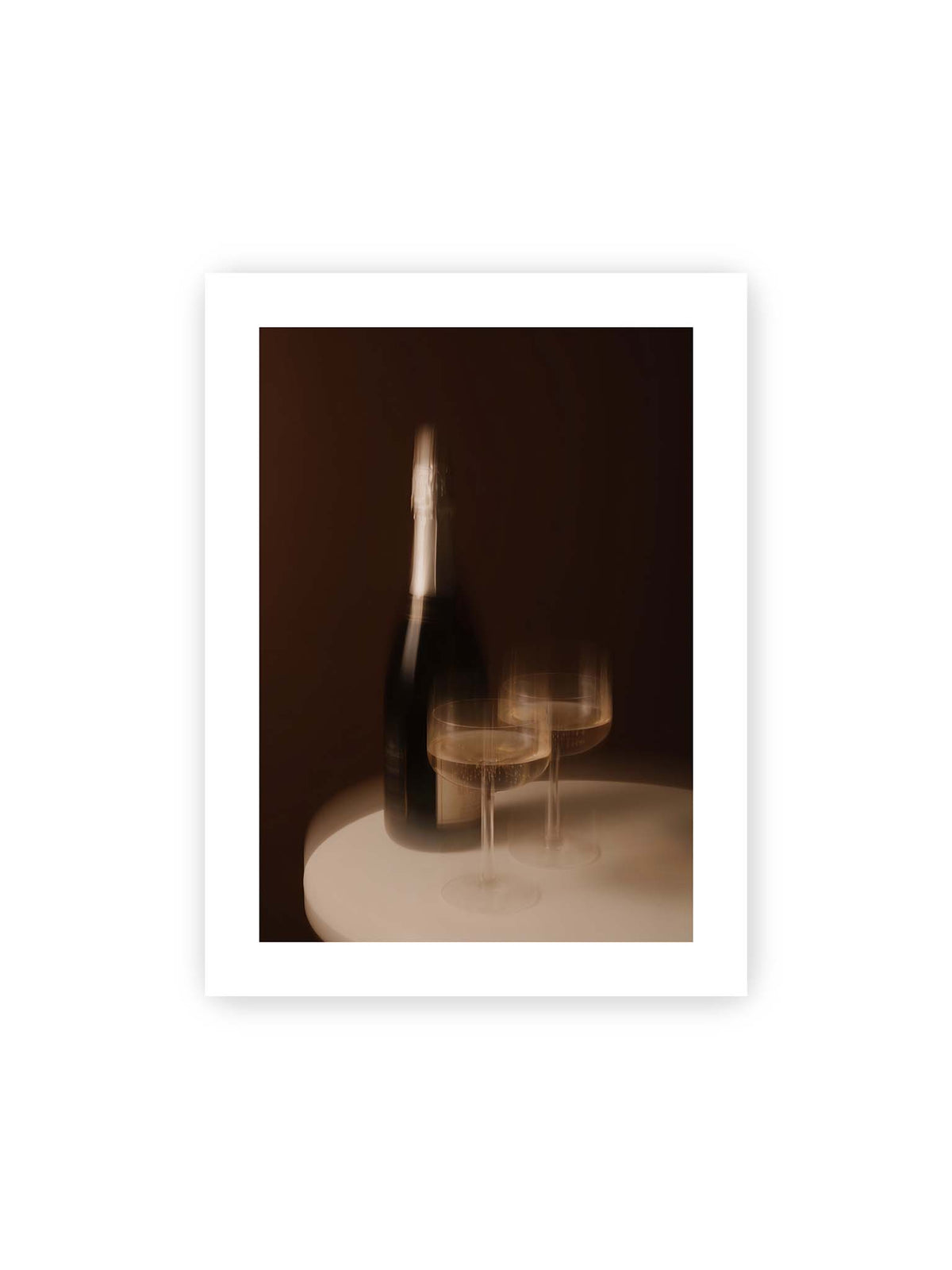 30x40 cm, weißer Galerie-Rand – Dunkle Flasche und zwei gefüllte Weingläser mit warmen Lichtreflexen auf einem runden hellen Tisch.