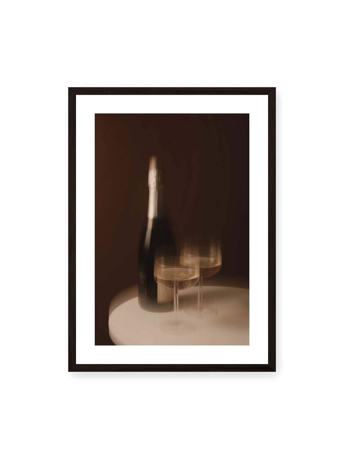 50x70 cm, weißer Galerie-Rand, schwarzer Rahmen – Dunkle Flasche und zwei gefüllte Weingläser mit warmen Lichtreflexen auf einem runden hellen Tisch.