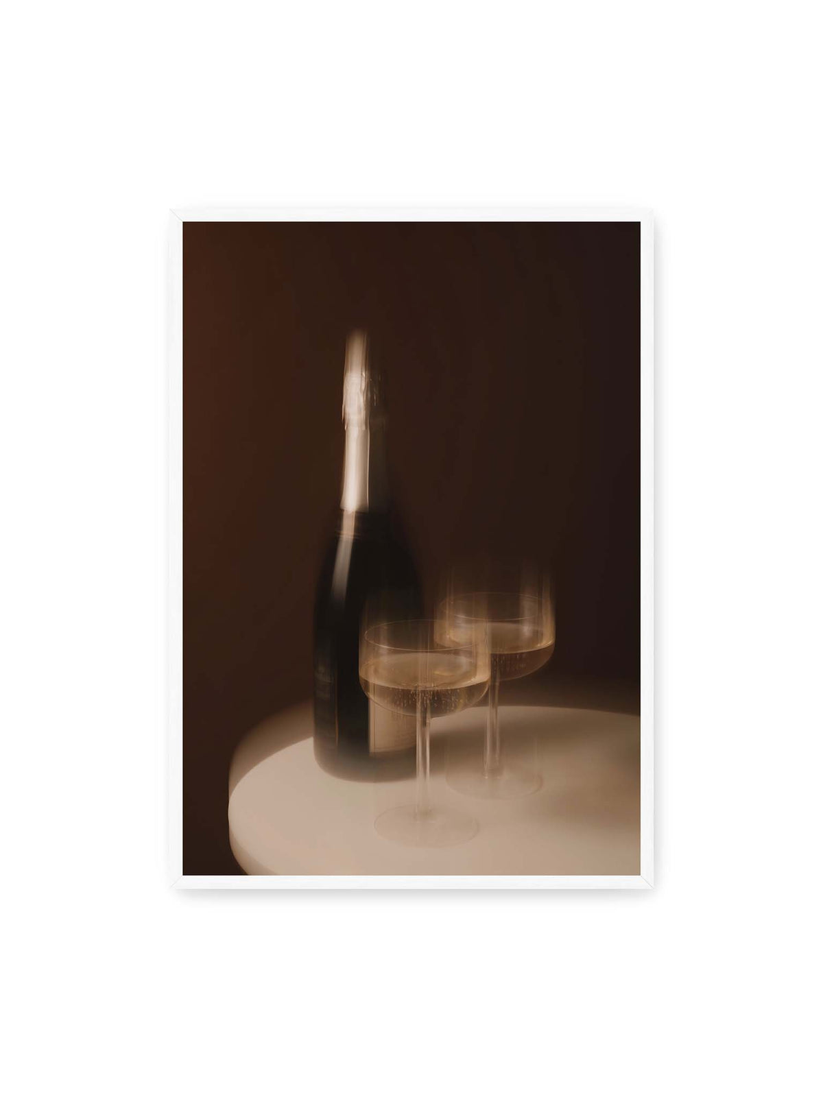 70x100 cm, weißer Rahmen – Dunkle Flasche und zwei gefüllte Weingläser mit warmen Lichtreflexen auf einem runden hellen Tisch.
