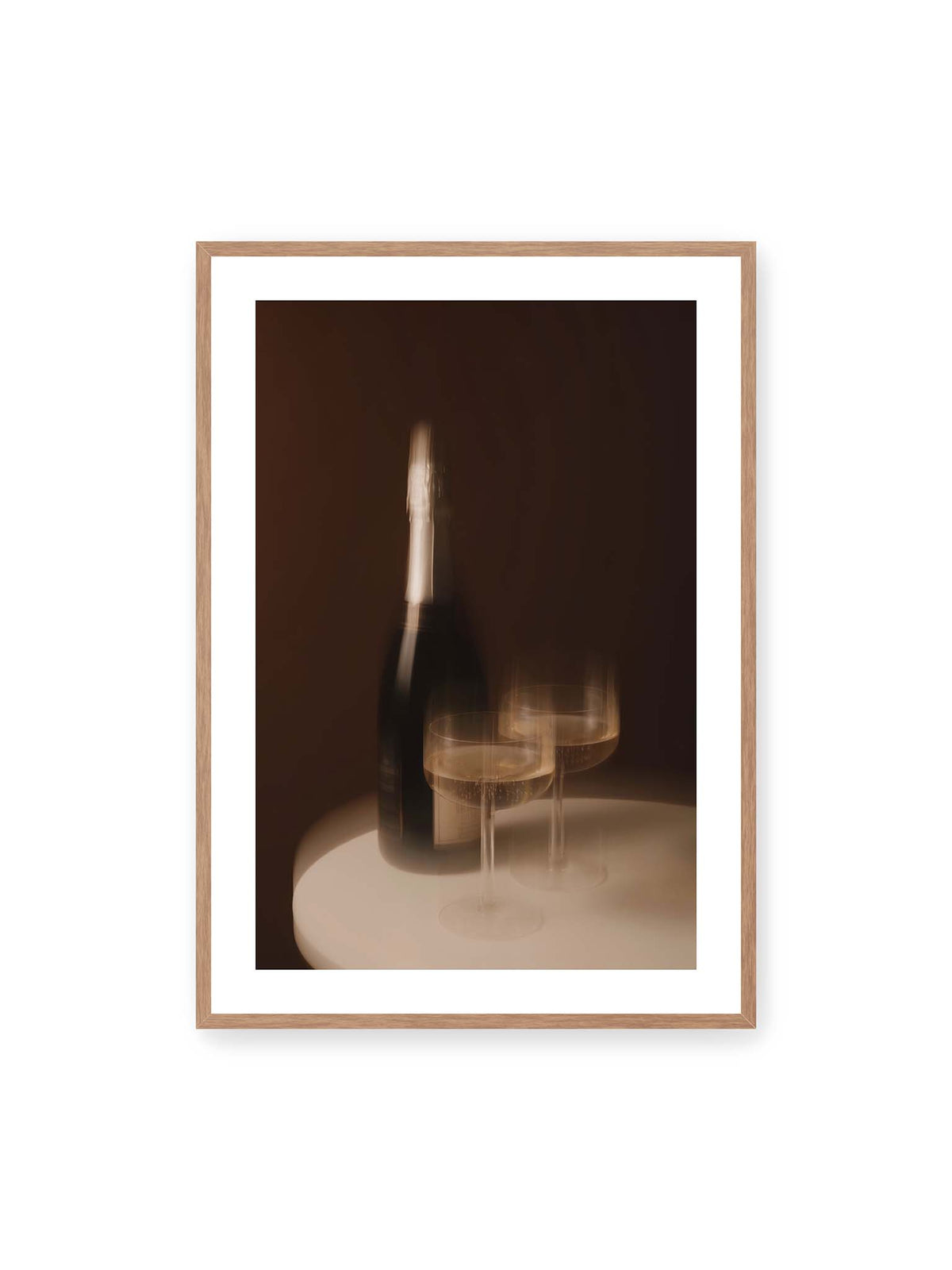 70x100 cm, weißer Galerie-Rand, Eichenrahmen – Dunkle Flasche und zwei gefüllte Weingläser mit warmen Lichtreflexen auf einem runden hellen Tisch.