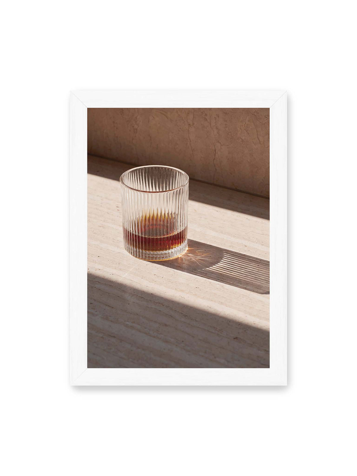 21x30 cm, weißer Rahmen – Geripptes Glas mit bernsteinfarbener Flüssigkeit auf heller Steinfläche im direkten Licht.