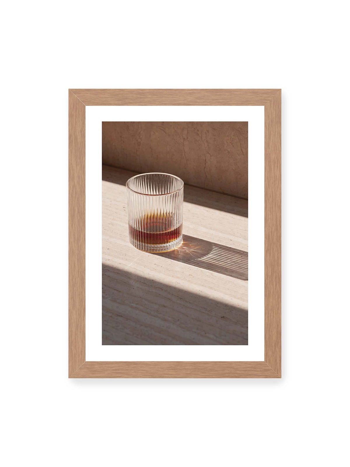 21x30 cm, weißer Galerie-Rand, Eichenrahmen – Geripptes Glas mit bernsteinfarbener Flüssigkeit auf heller Steinfläche im direkten Licht.