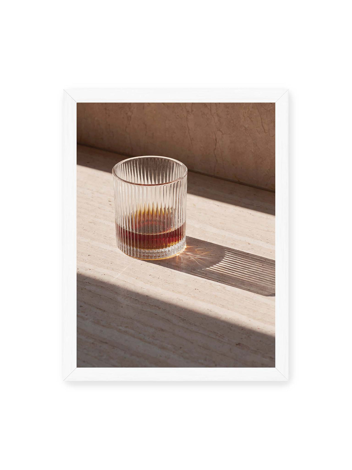 30x40 cm, weißer Rahmen – Geripptes Glas mit bernsteinfarbener Flüssigkeit auf heller Steinfläche im direkten Licht.