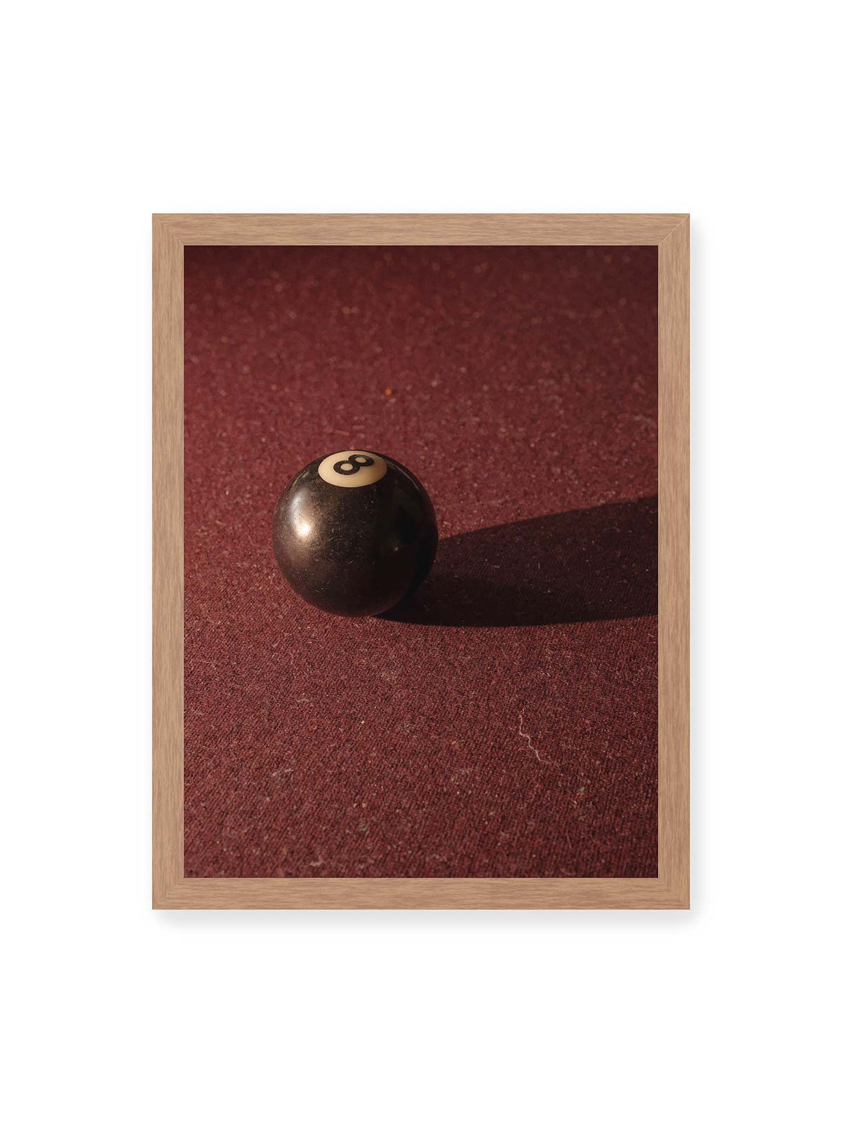 30x40 cm, Eichenrahmen – Schwarze Billardkugel auf tiefroter Spielfläche mit langem Schatten im seitlichen Licht.