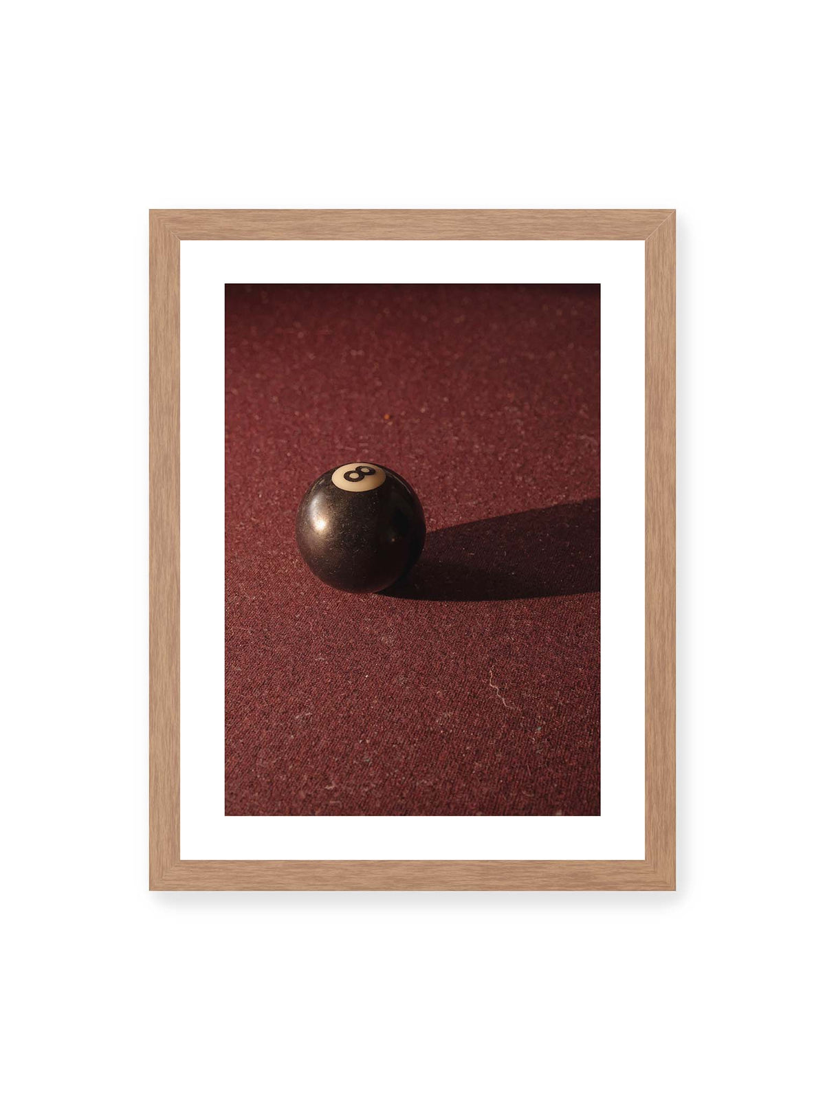 30x40 cm, weißer Galerie-Rand, Eichenrahmen – Schwarze Billardkugel auf tiefroter Spielfläche mit langem Schatten im seitlichen Licht.