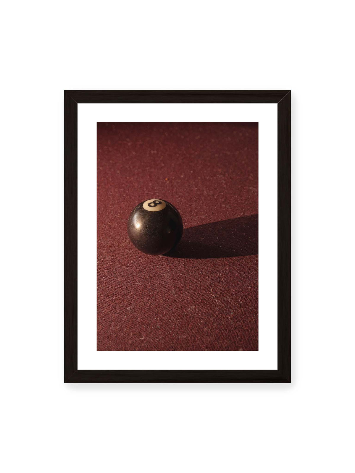 30x40 cm, weißer Galerie-Rand, schwarzer Rahmen – Schwarze Billardkugel auf tiefroter Spielfläche mit langem Schatten im seitlichen Licht.