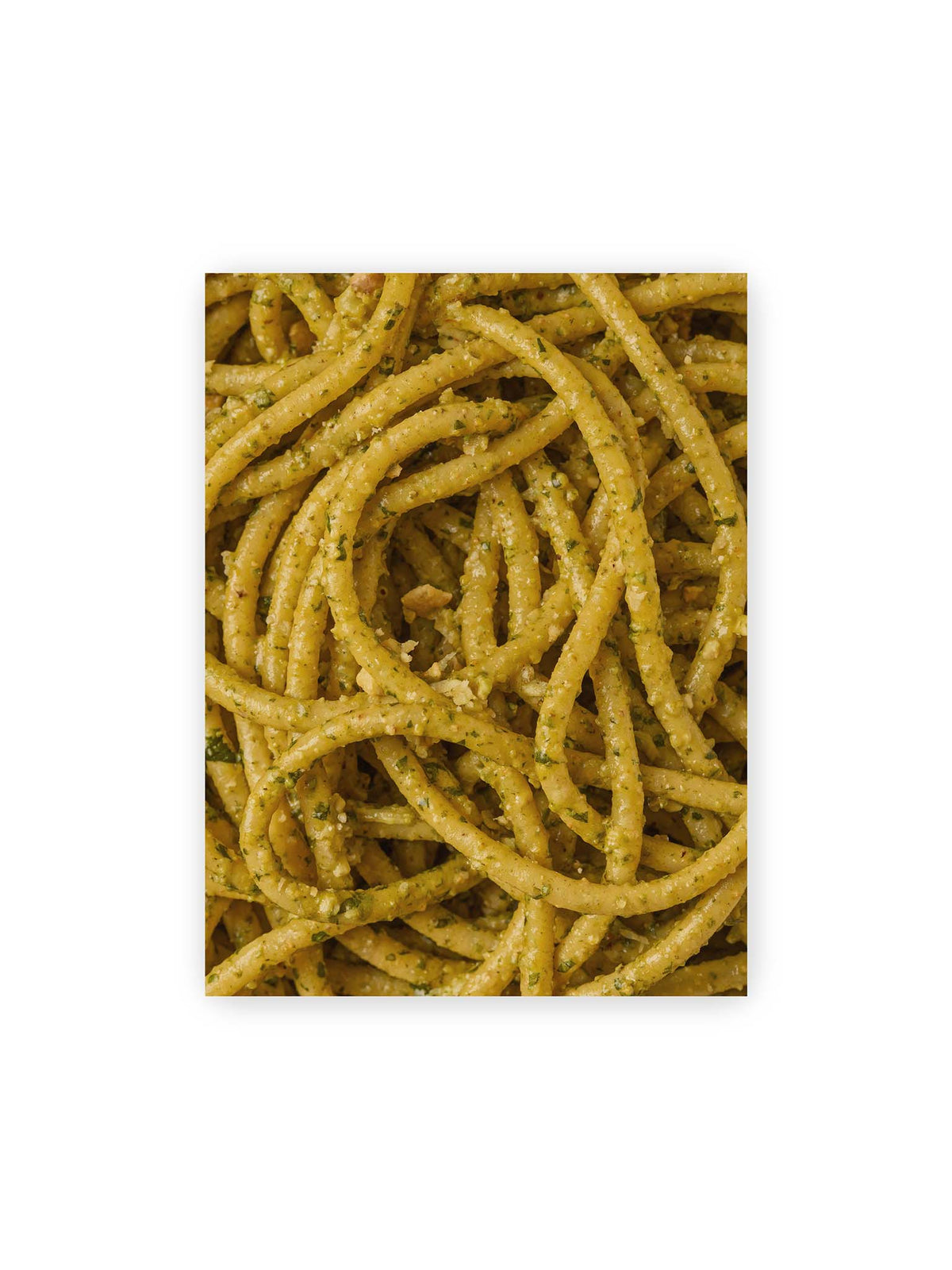 30x40 cm – Eng verschlungene Pasta mit grünlich gelber Sauce und feinen Kräuterstücken in dichter Nahaufnahme.