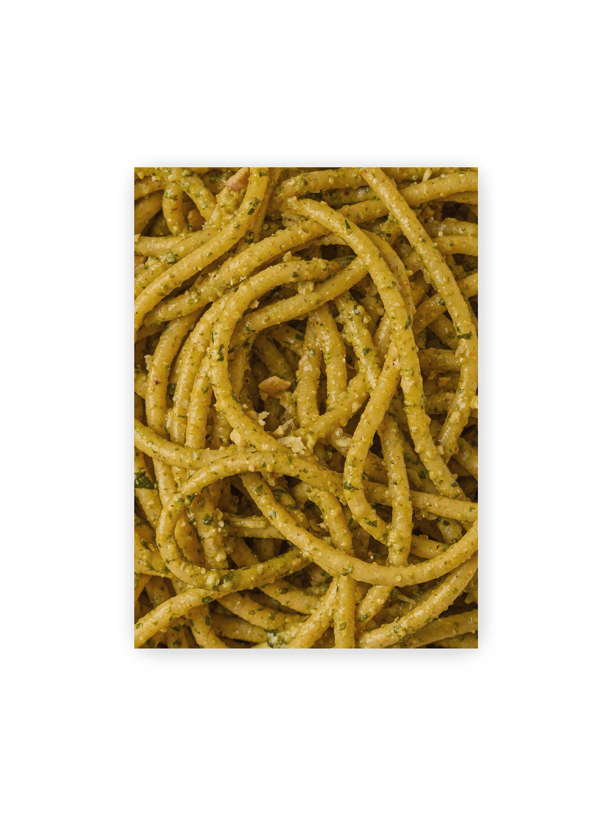 50x70 cm – Eng verschlungene Pasta mit grünlich gelber Sauce und feinen Kräuterstücken in dichter Nahaufnahme.