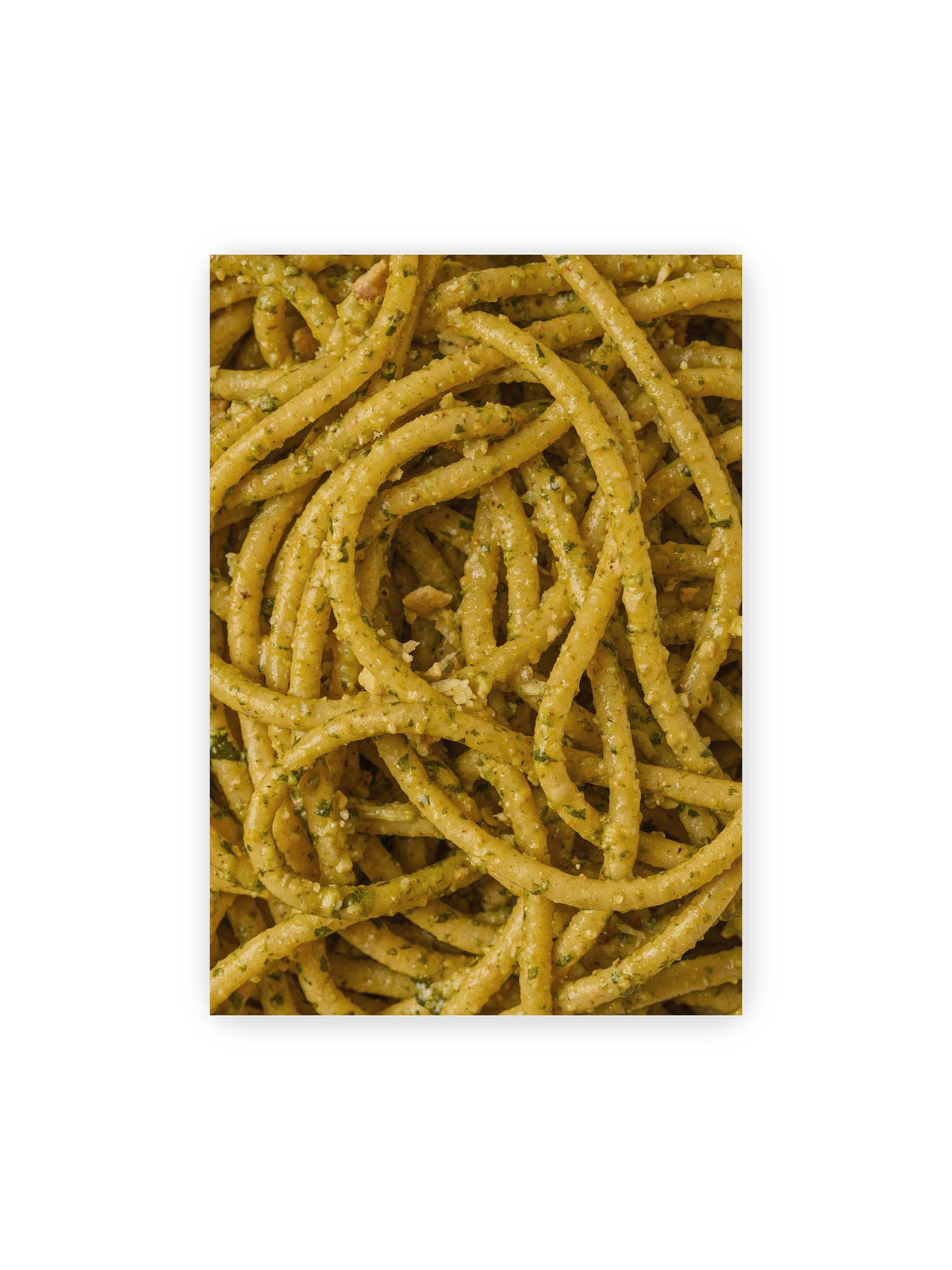70x100 cm – Eng verschlungene Pasta mit grünlich gelber Sauce und feinen Kräuterstücken in dichter Nahaufnahme.