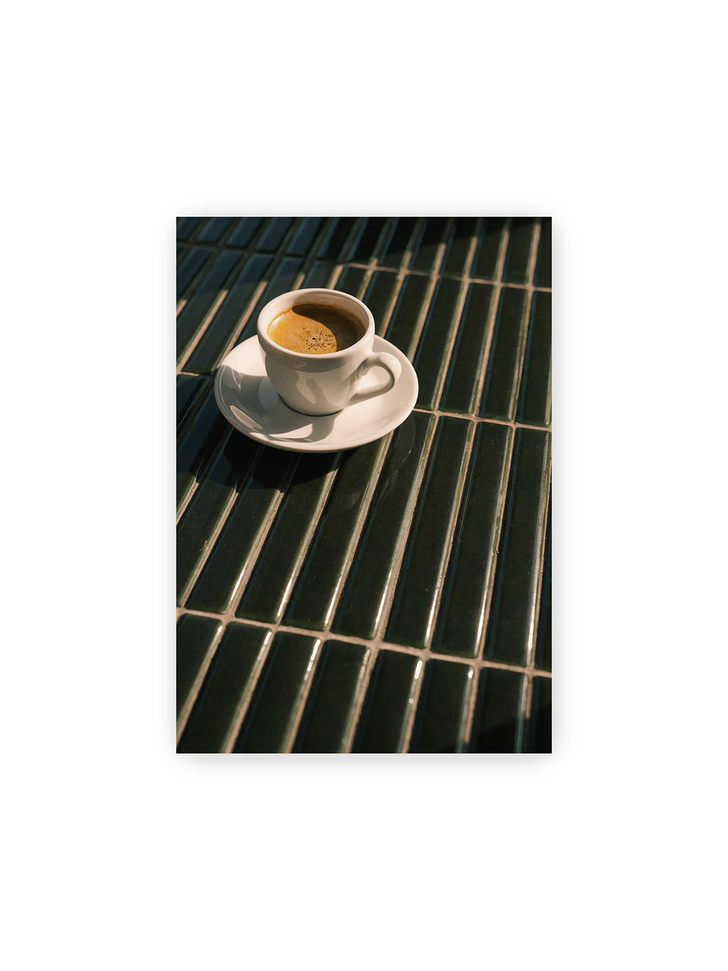 21x30 cm – Weiße Espressotasse auf dunkelgrünen Fliesen im direkten Licht mit geometrischen Schatten.
