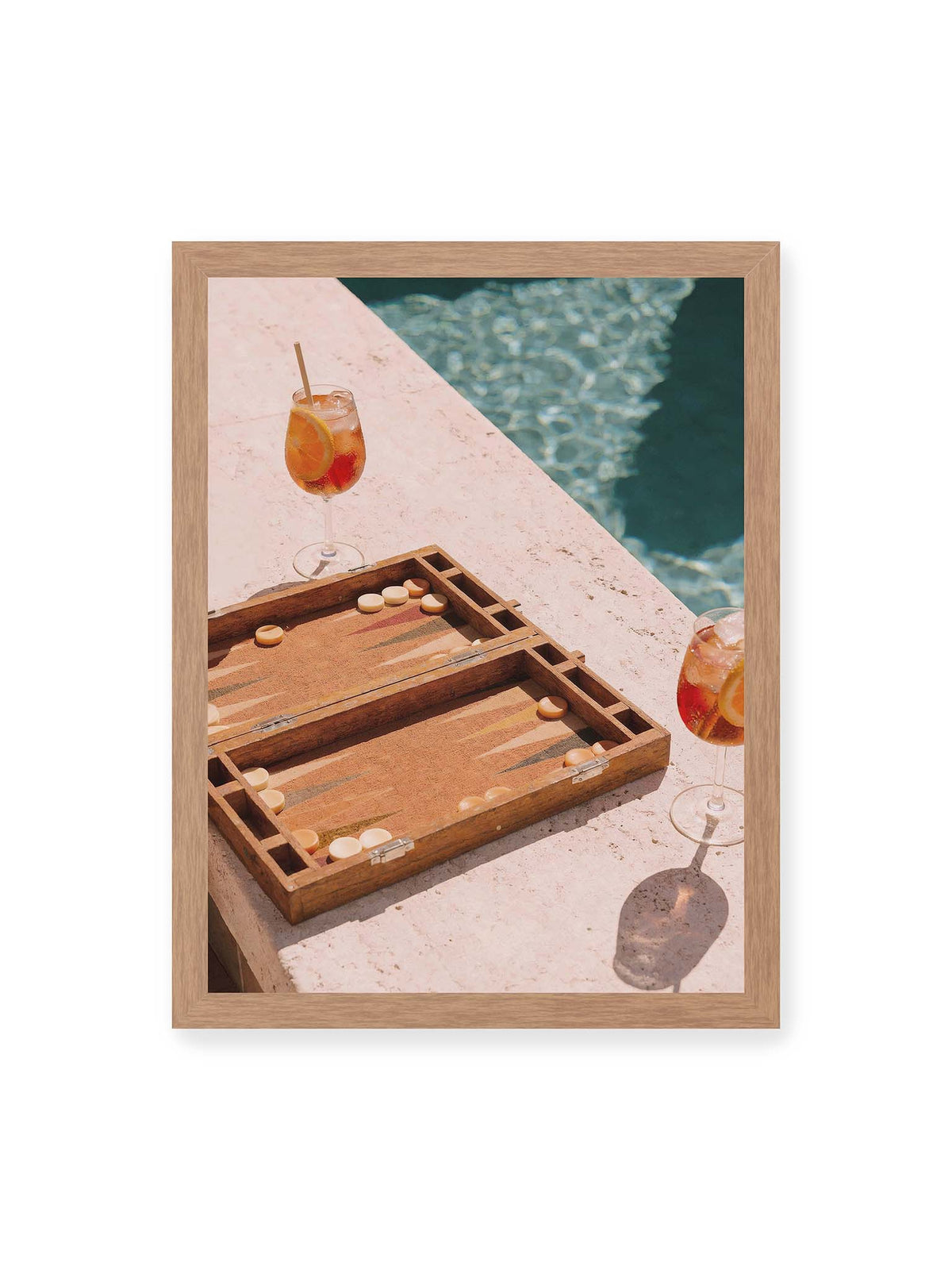 30x40 cm, Eichenrahmen – Geöffnetes Backgammonbrett mit zwei orangefarbenen Drinks auf heller Steinfläche neben blauem Wasser.