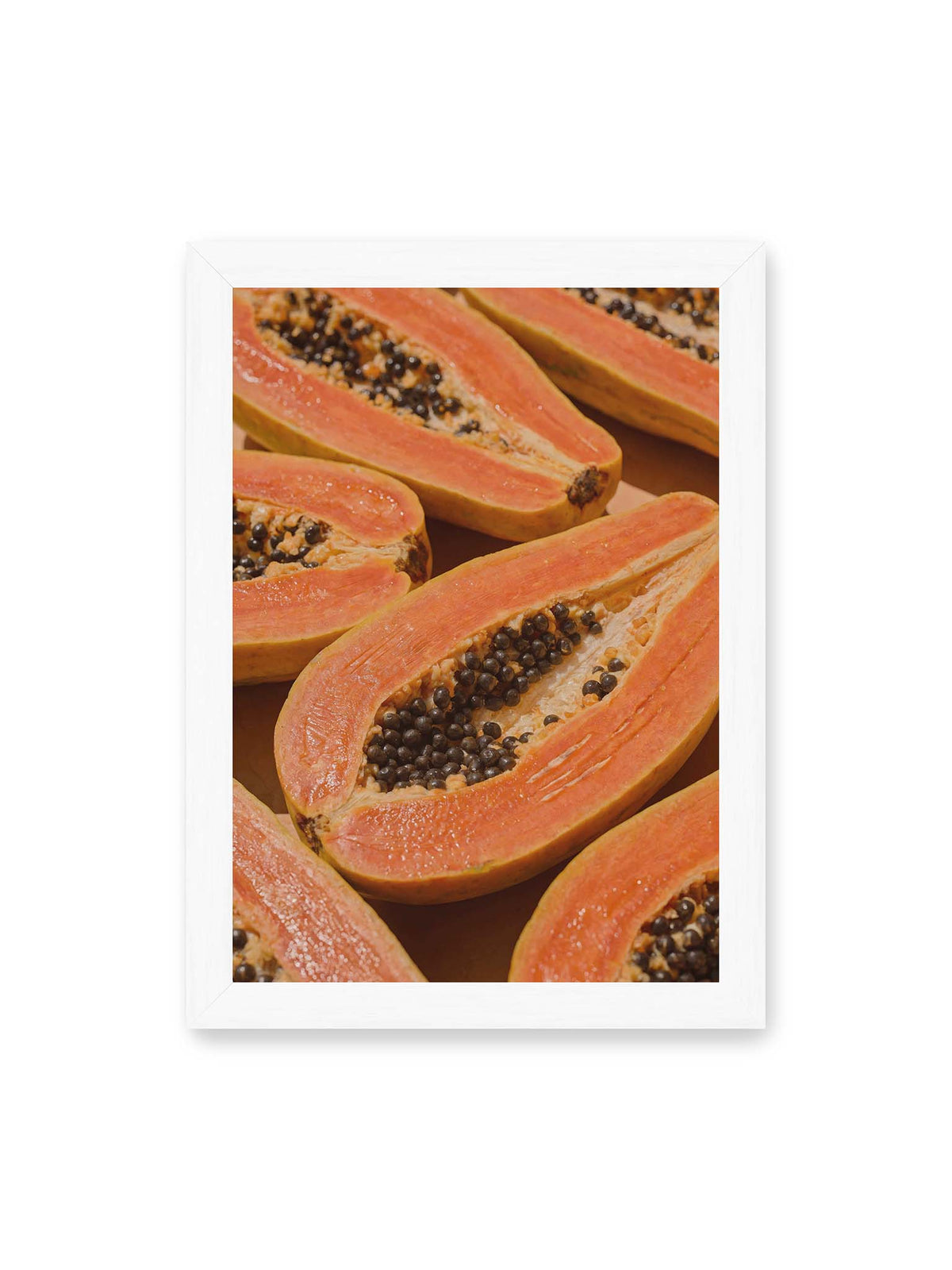 21x30 cm, weißer Rahmen – Aufgeschnittene Papayas mit orangefarbenem Fruchtfleisch und zahlreichen dunklen Kernen in enger Nahaufnahme.