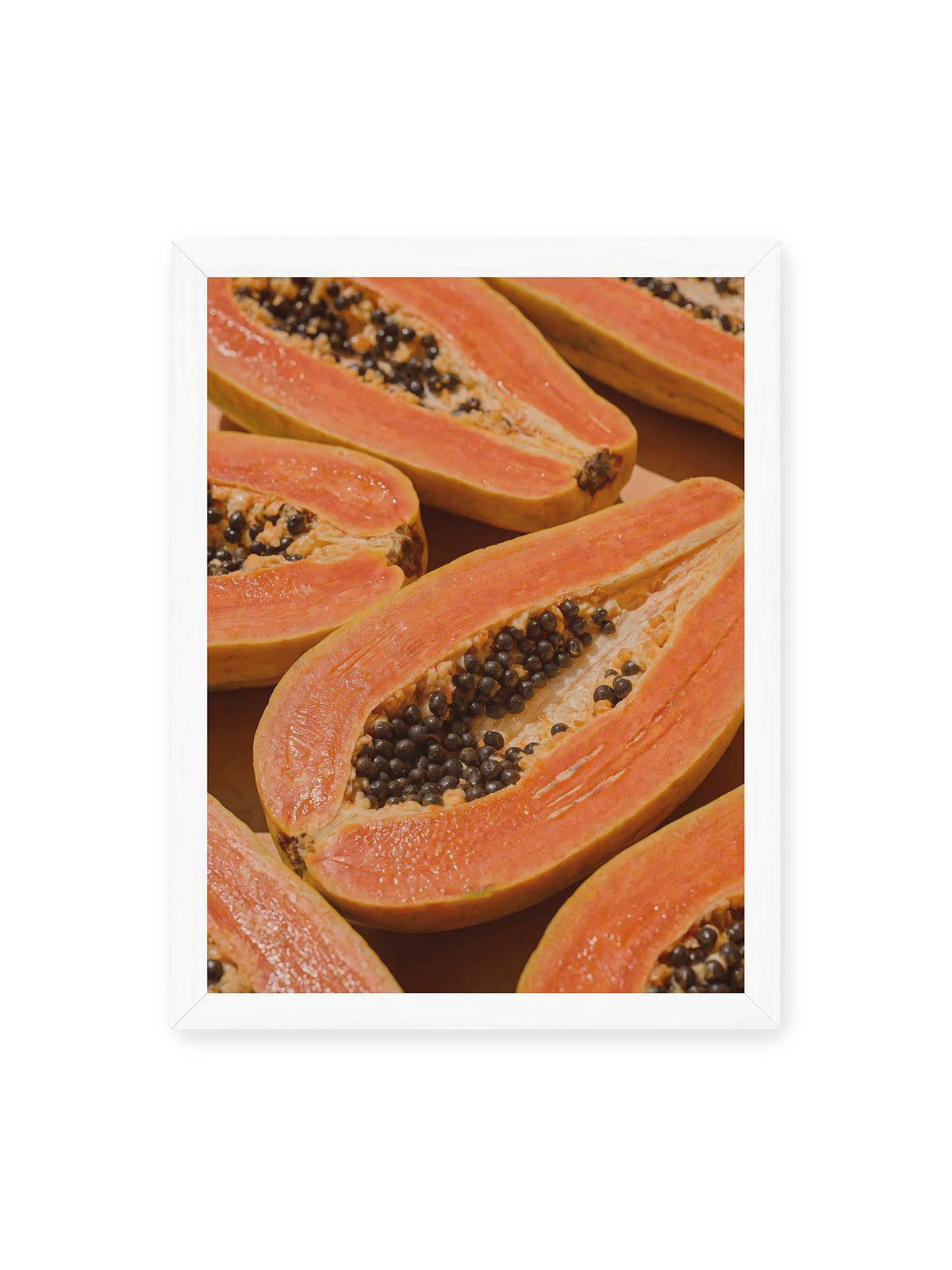 30x40 cm, weißer Rahmen – Aufgeschnittene Papayas mit orangefarbenem Fruchtfleisch und zahlreichen dunklen Kernen in enger Nahaufnahme.