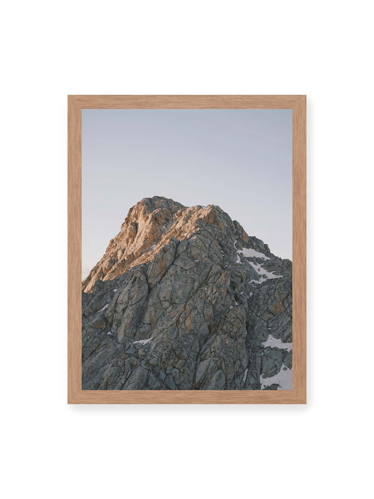 30x40 cm, Eichenrahmen – Massiver grauer Felsgipfel mit kleinen Schneefeldern vor einem weiten blassblauen Himmel.