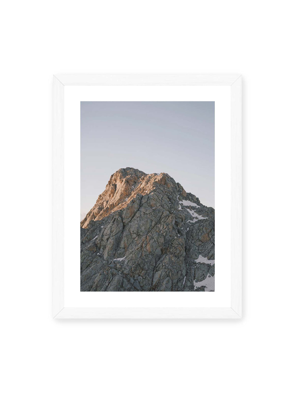 30x40 cm, weißer Galerie-Rand, weißer Rahmen – Massiver grauer Felsgipfel mit kleinen Schneefeldern vor einem weiten blassblauen Himmel.