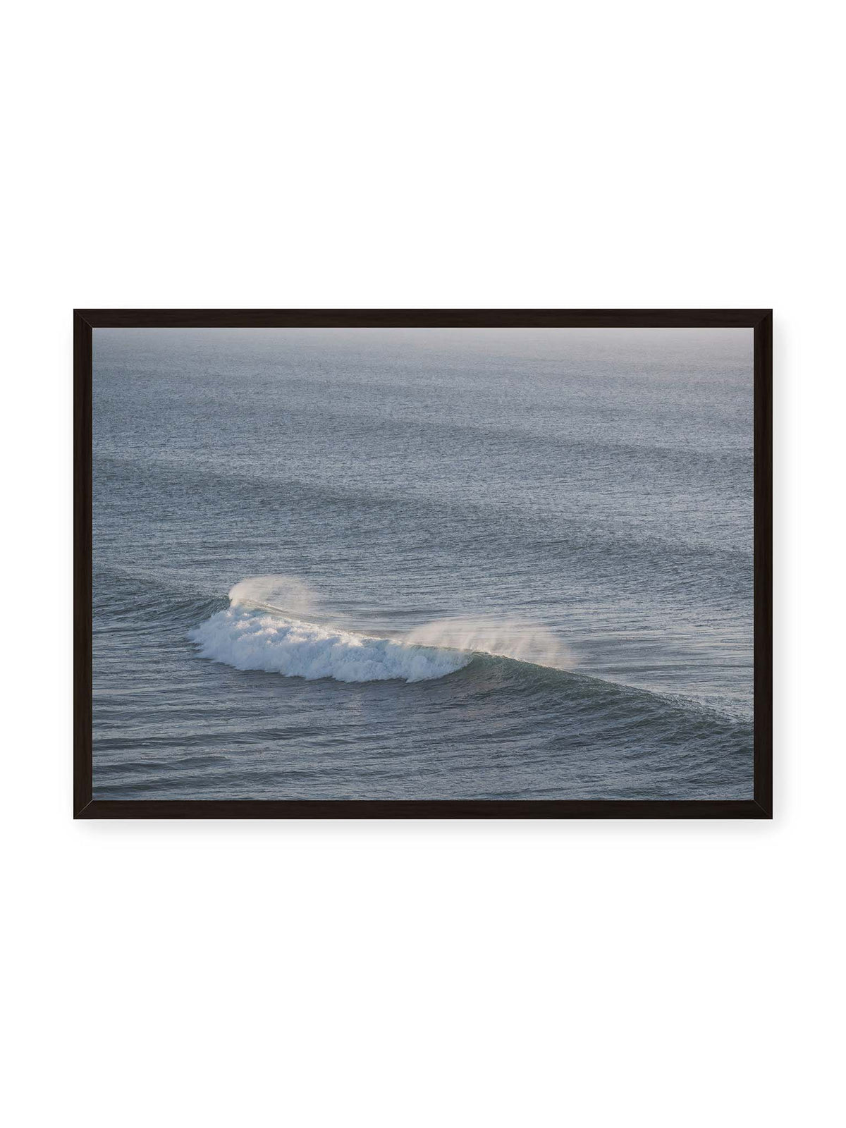 70x50 cm, schwarzer Rahmen – Brechende Welle mit weißem Schaum und feiner Gischt auf einer weiten blau-grauen Wasserfläche.