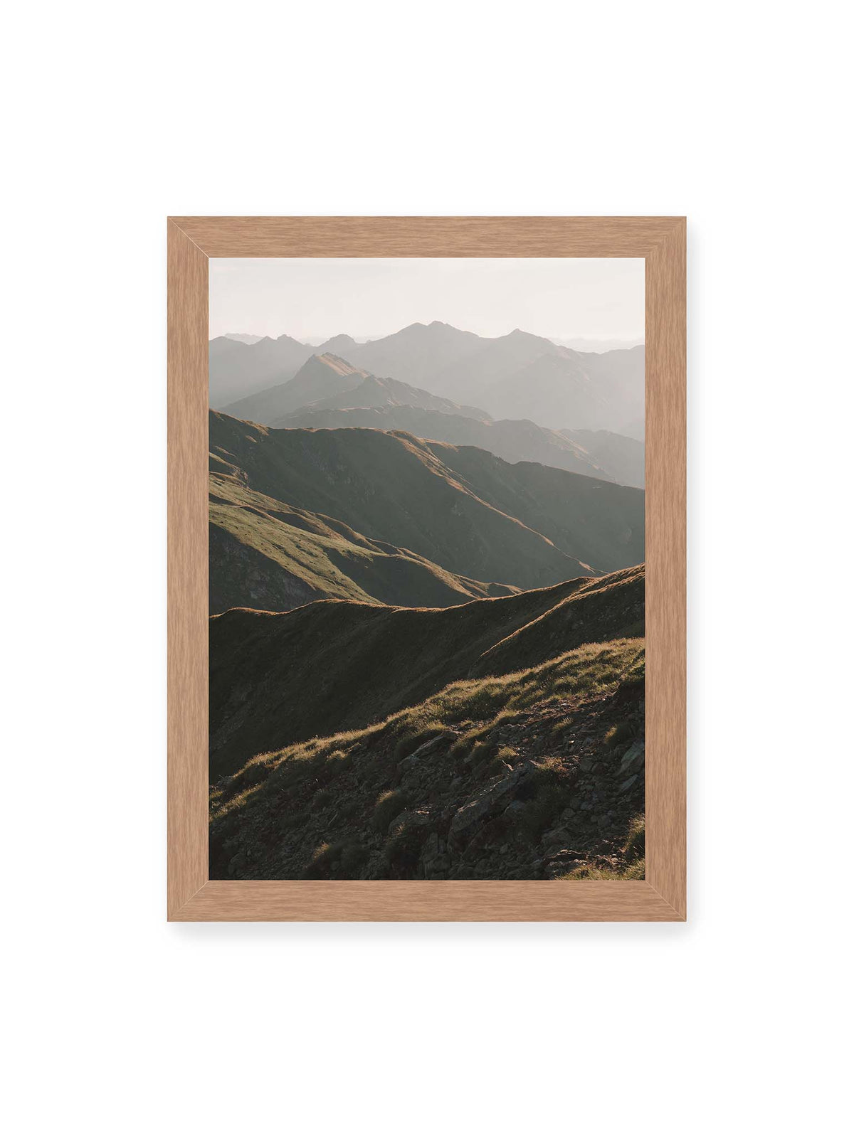 21x30 cm, Eichenrahmen – Gestaffelte Bergketten mit grasbewachsenen Hängen und warm beleuchteten Konturen unter hellem Himmel.
