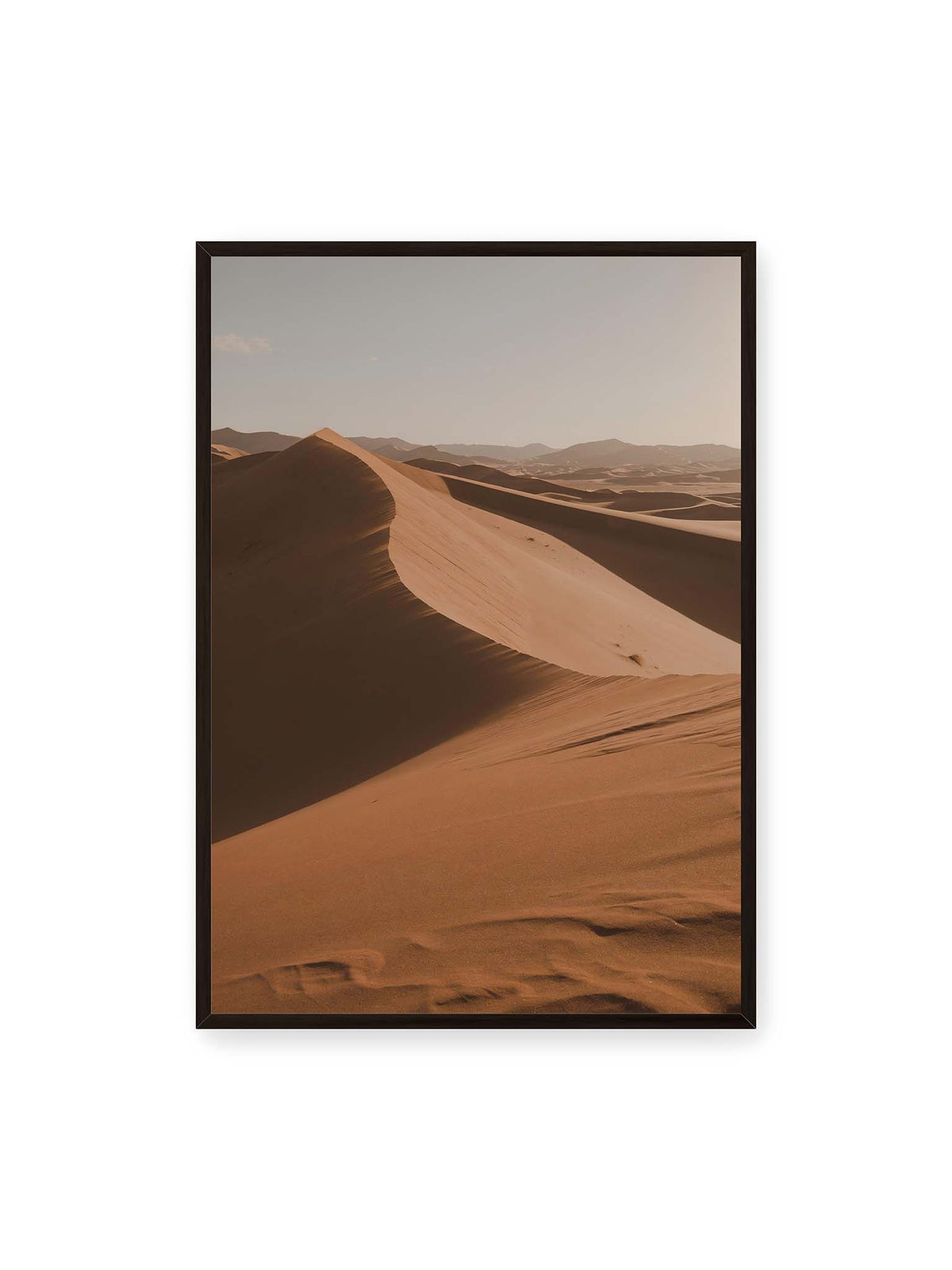 70x100 cm, schwarzer Rahmen – Geschwungene Sanddünen mit warm beleuchteten Kämmen und tiefen Schatten vor einem hellen Himmel.