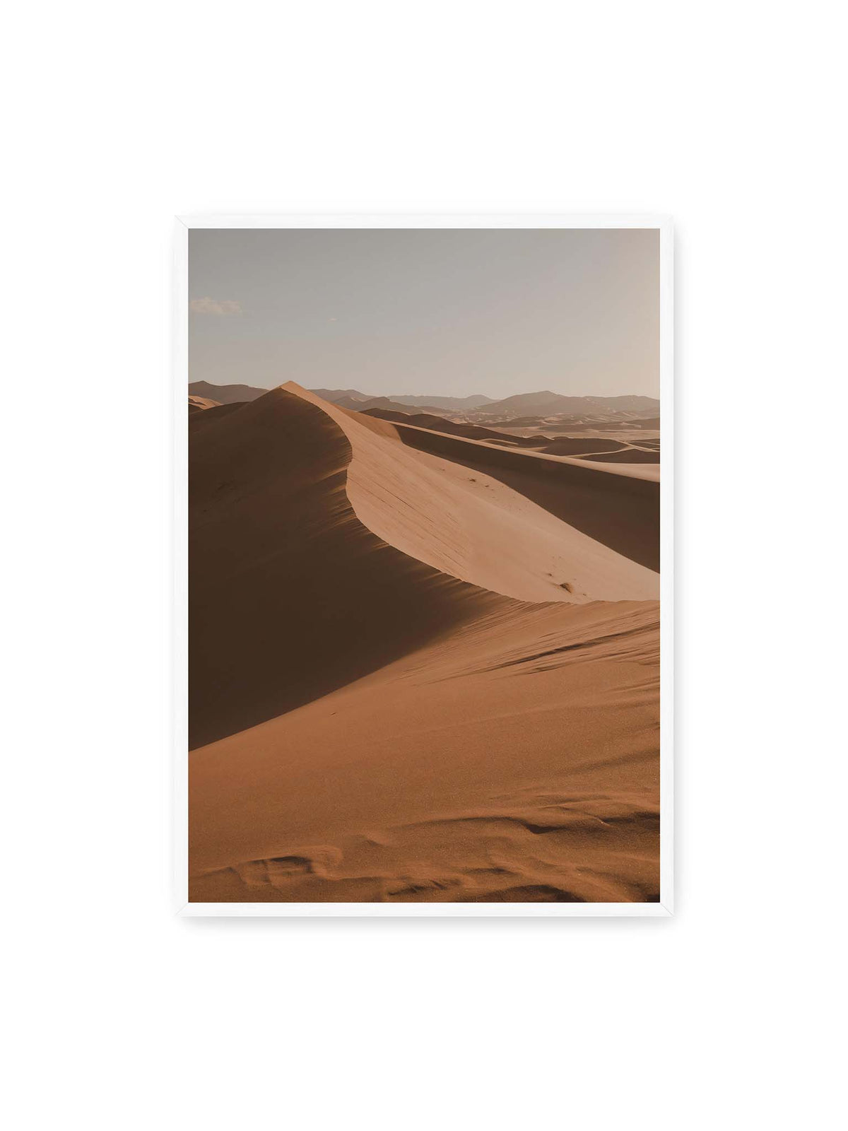 70x100 cm, weißer Rahmen – Geschwungene Sanddünen mit warm beleuchteten Kämmen und tiefen Schatten vor einem hellen Himmel.