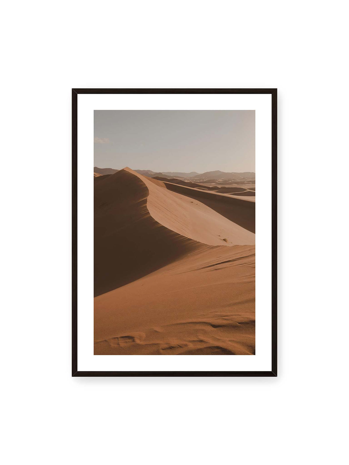 70x100 cm, weißer Galerie-Rand, schwarzer Rahmen – Geschwungene Sanddünen mit warm beleuchteten Kämmen und tiefen Schatten vor einem hellen Himmel.