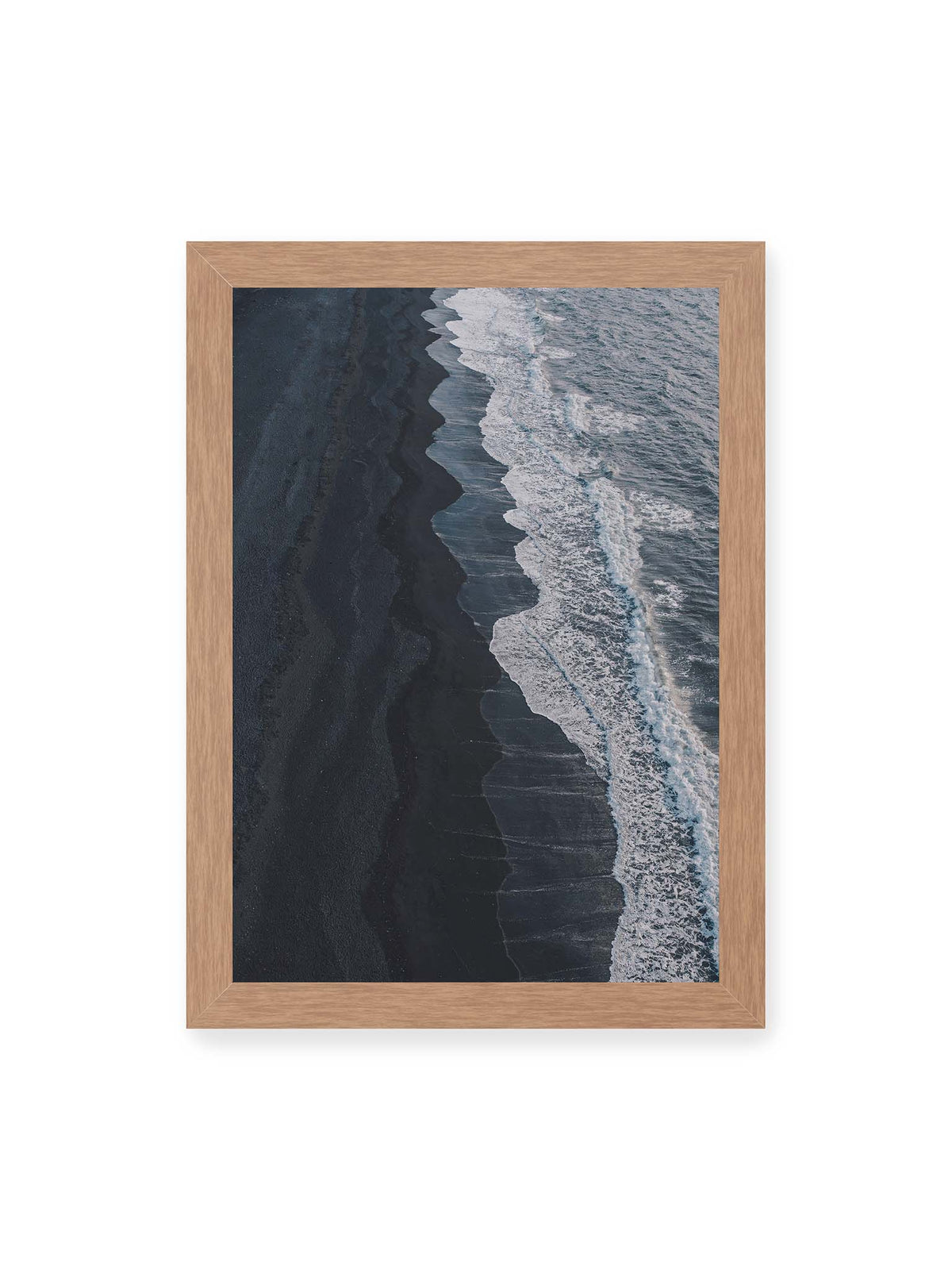 21x30 cm, Eichenrahmen – Dunkler Strand aus erhöhter Perspektive mit weißer Brandung und blau-grauem Meer entlang einer geschwungenen Küstenlinie.