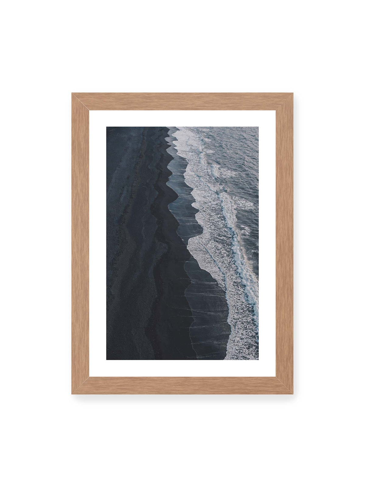 21x30 cm, weißer Galerie-Rand, Eichenrahmen – Dunkler Strand aus erhöhter Perspektive mit weißer Brandung und blau-grauem Meer entlang einer geschwungenen Küstenlinie.