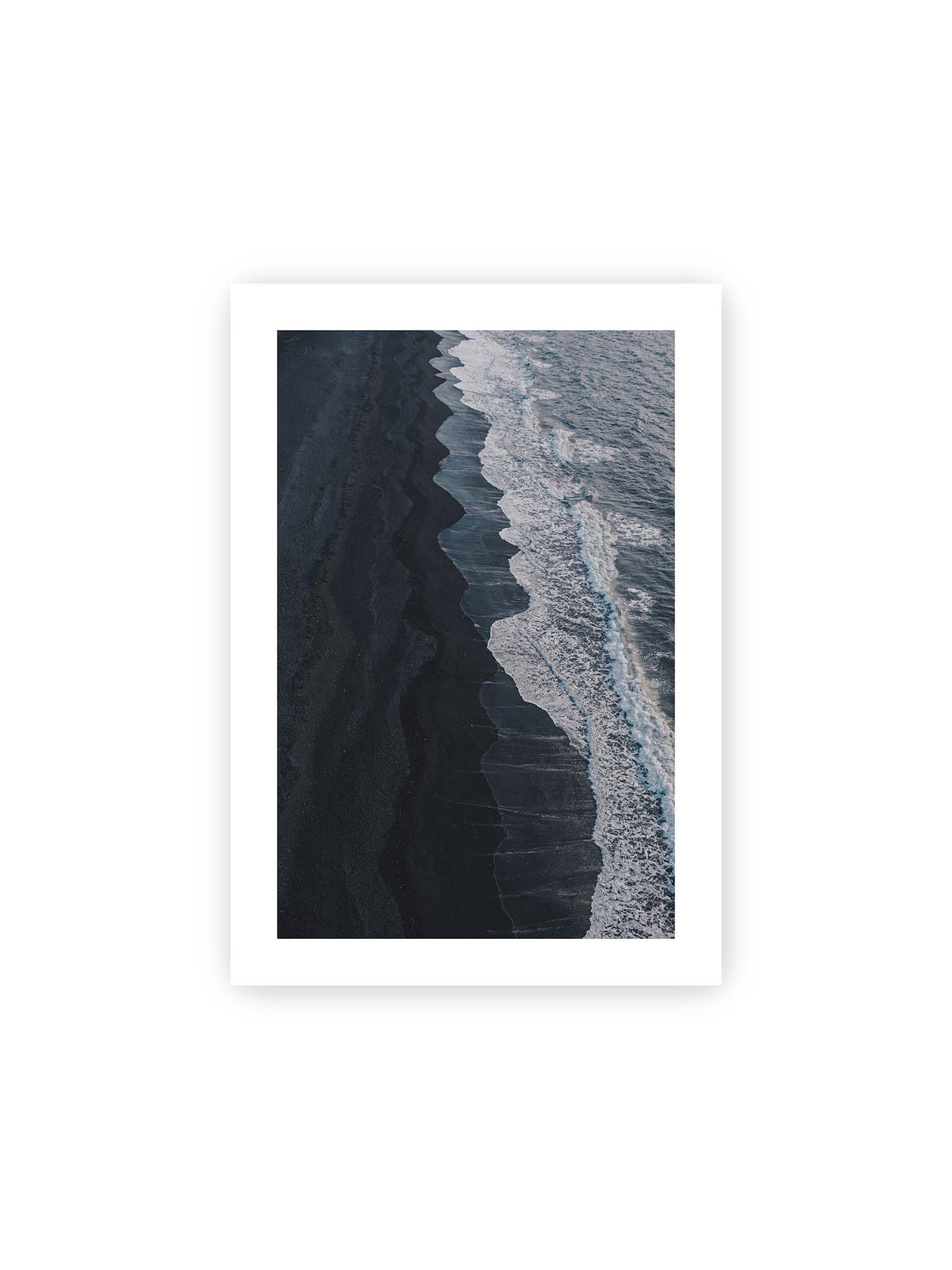 21x30 cm, weißer Galerie-Rand – Dunkler Strand aus erhöhter Perspektive mit weißer Brandung und blau-grauem Meer entlang einer geschwungenen Küstenlinie.