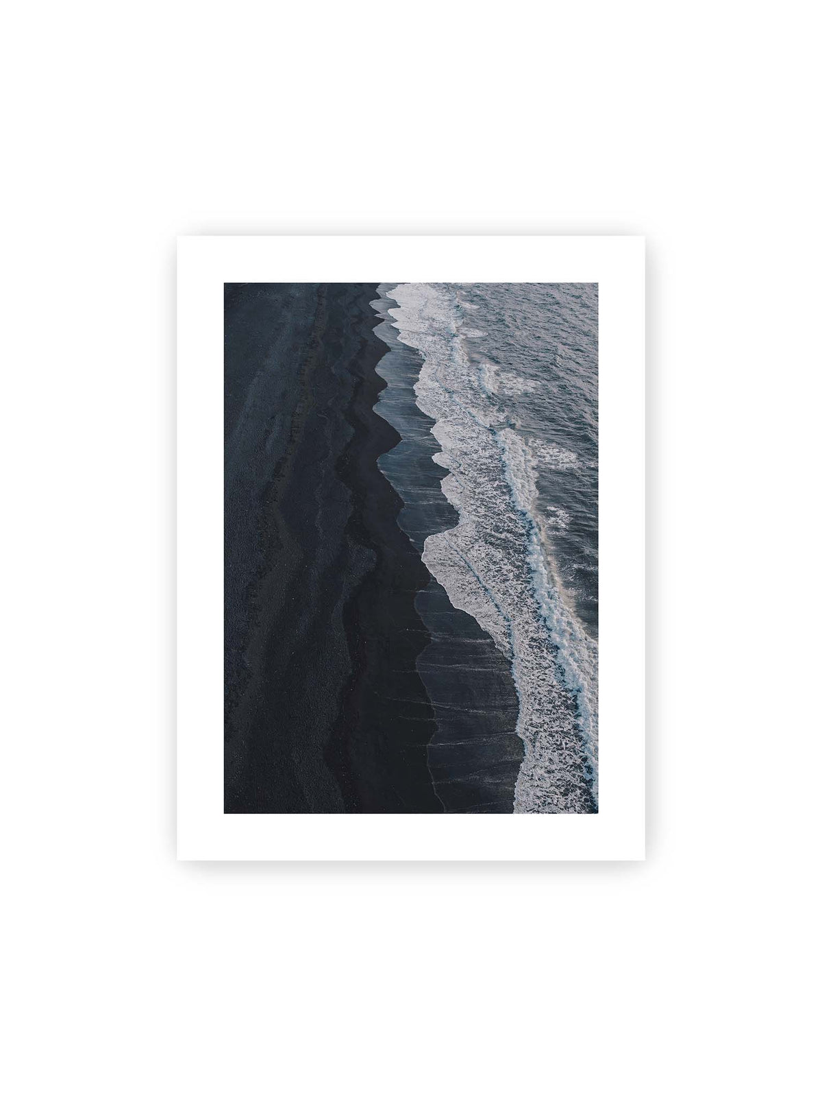 30x40 cm, weißer Galerie-Rand – Dunkler Strand aus erhöhter Perspektive mit weißer Brandung und blau-grauem Meer entlang einer geschwungenen Küstenlinie.