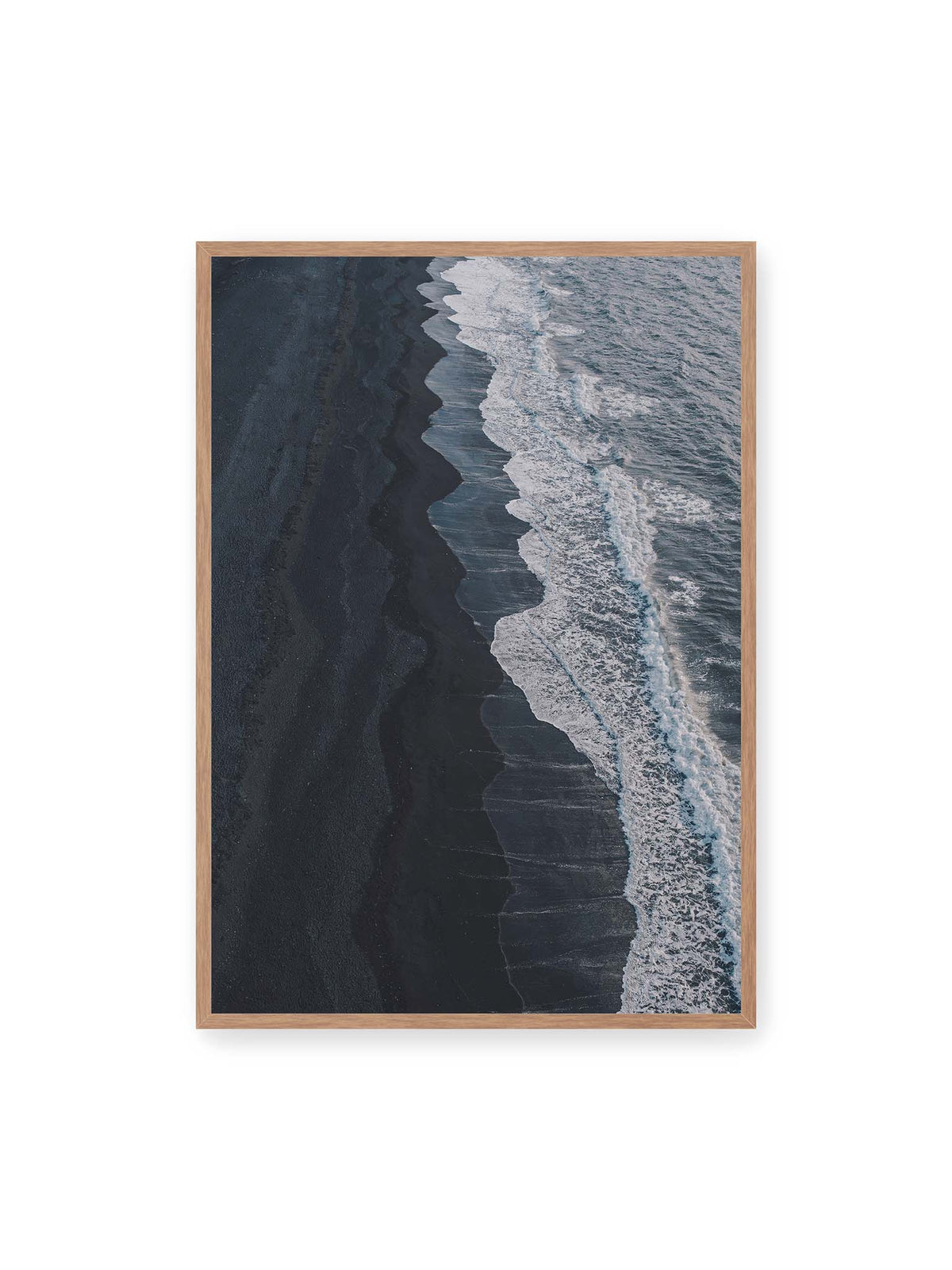70x100 cm, Eichenrahmen – Dunkler Strand aus erhöhter Perspektive mit weißer Brandung und blau-grauem Meer entlang einer geschwungenen Küstenlinie.