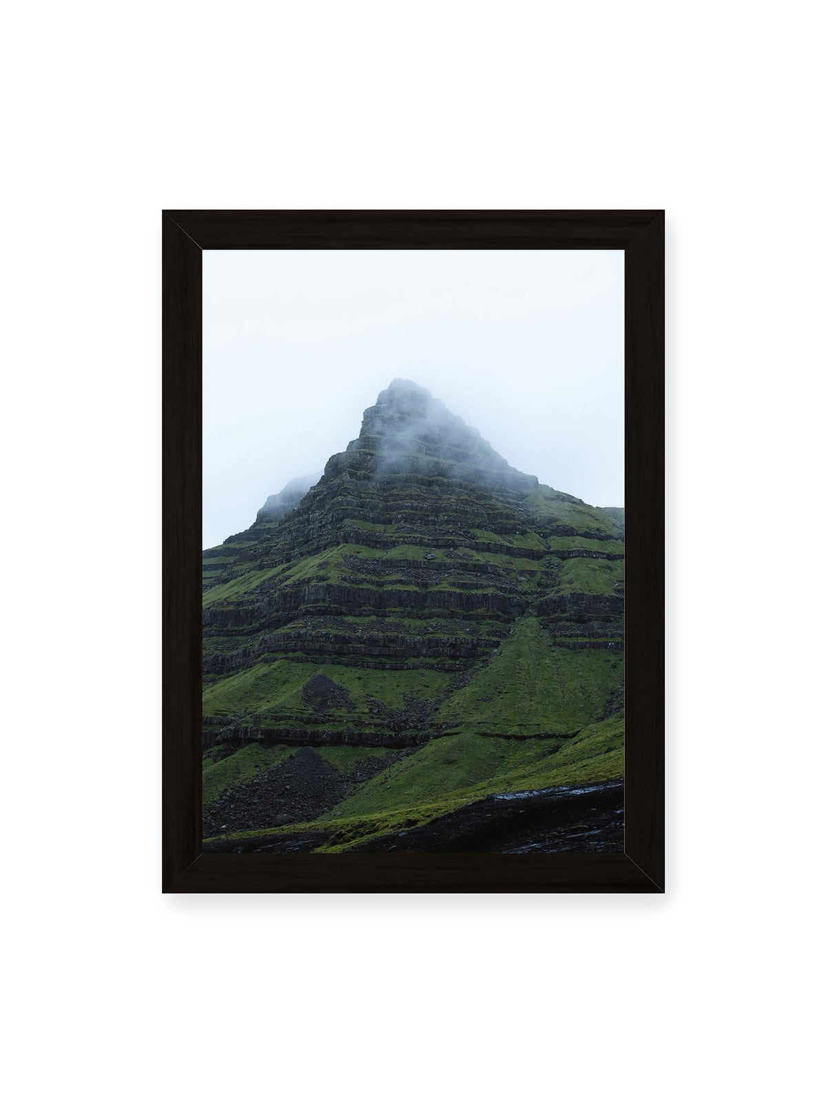 21x30 cm, schwarzer Rahmen – Steiler grüner Berg mit dunklen Felsbändern, dessen Gipfel in dichtem Nebel verschwindet.