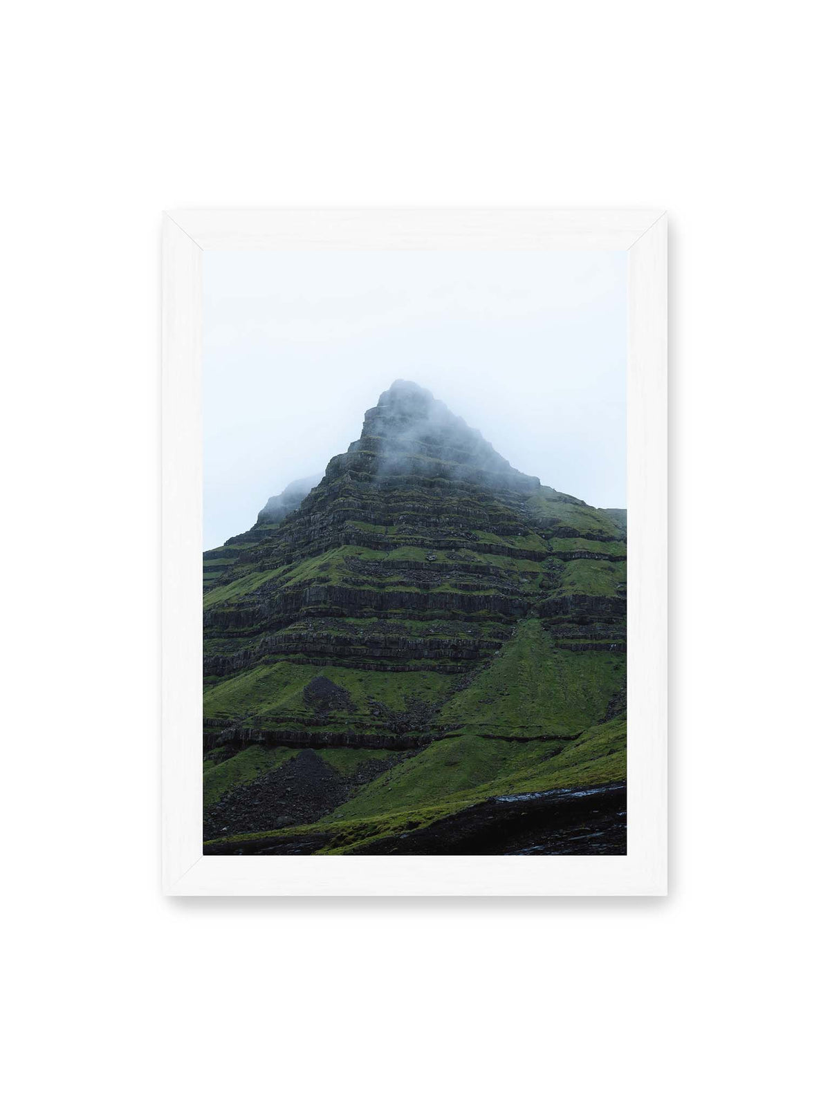 21x30 cm, weißer Rahmen – Steiler grüner Berg mit dunklen Felsbändern, dessen Gipfel in dichtem Nebel verschwindet.