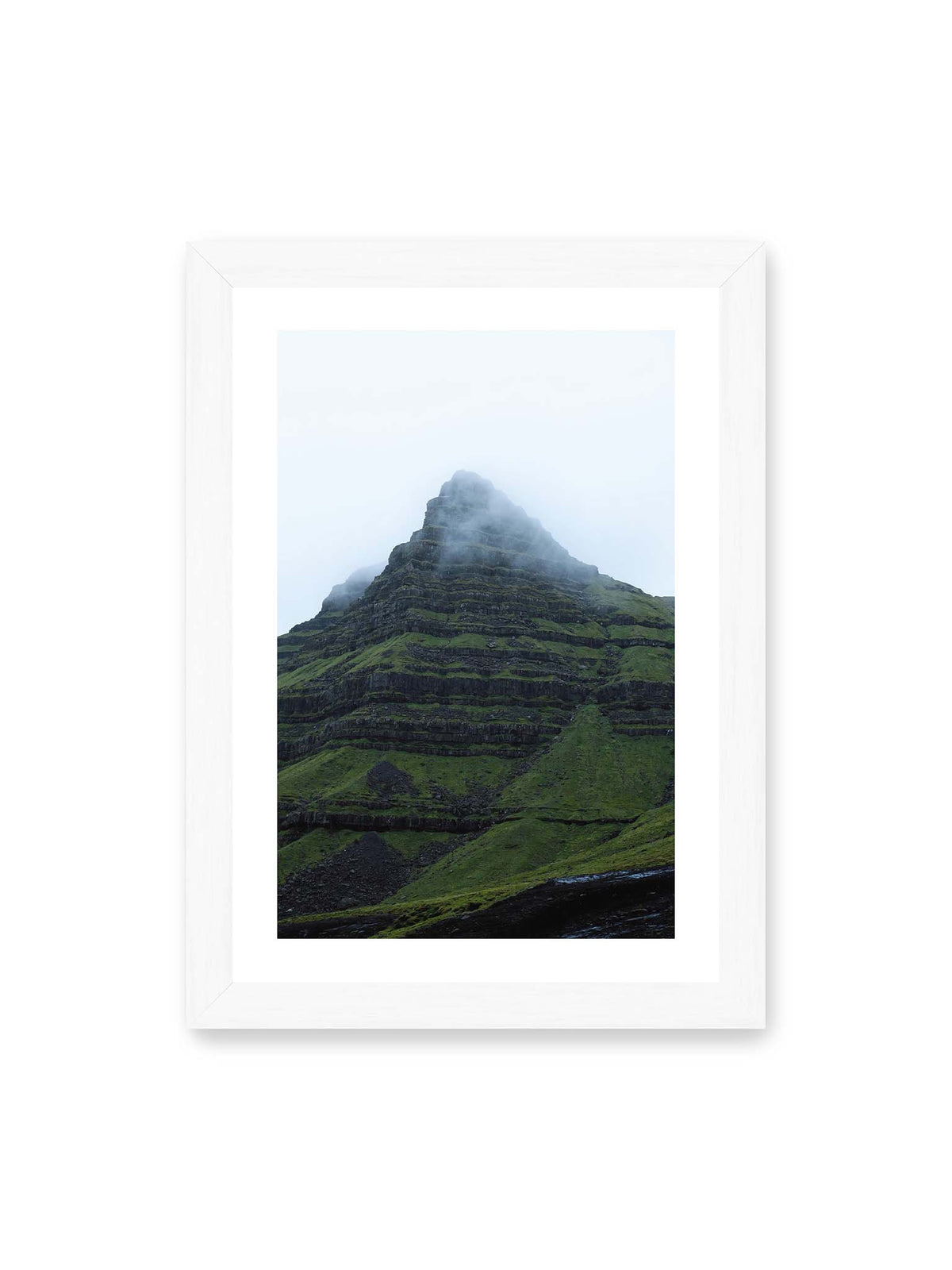 21x30 cm, weißer Galerie-Rand, weißer Rahmen – Steiler grüner Berg mit dunklen Felsbändern, dessen Gipfel in dichtem Nebel verschwindet.