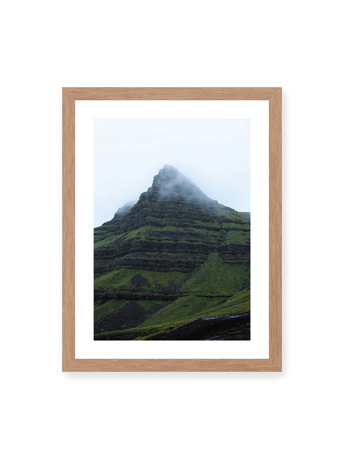 30x40 cm, weißer Galerie-Rand, Eichenrahmen – Steiler grüner Berg mit dunklen Felsbändern, dessen Gipfel in dichtem Nebel verschwindet.