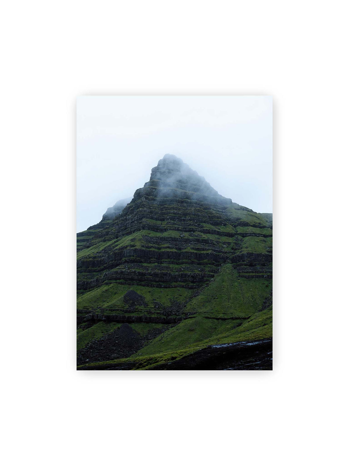 50x70 cm – Steiler grüner Berg mit dunklen Felsbändern, dessen Gipfel in dichtem Nebel verschwindet.