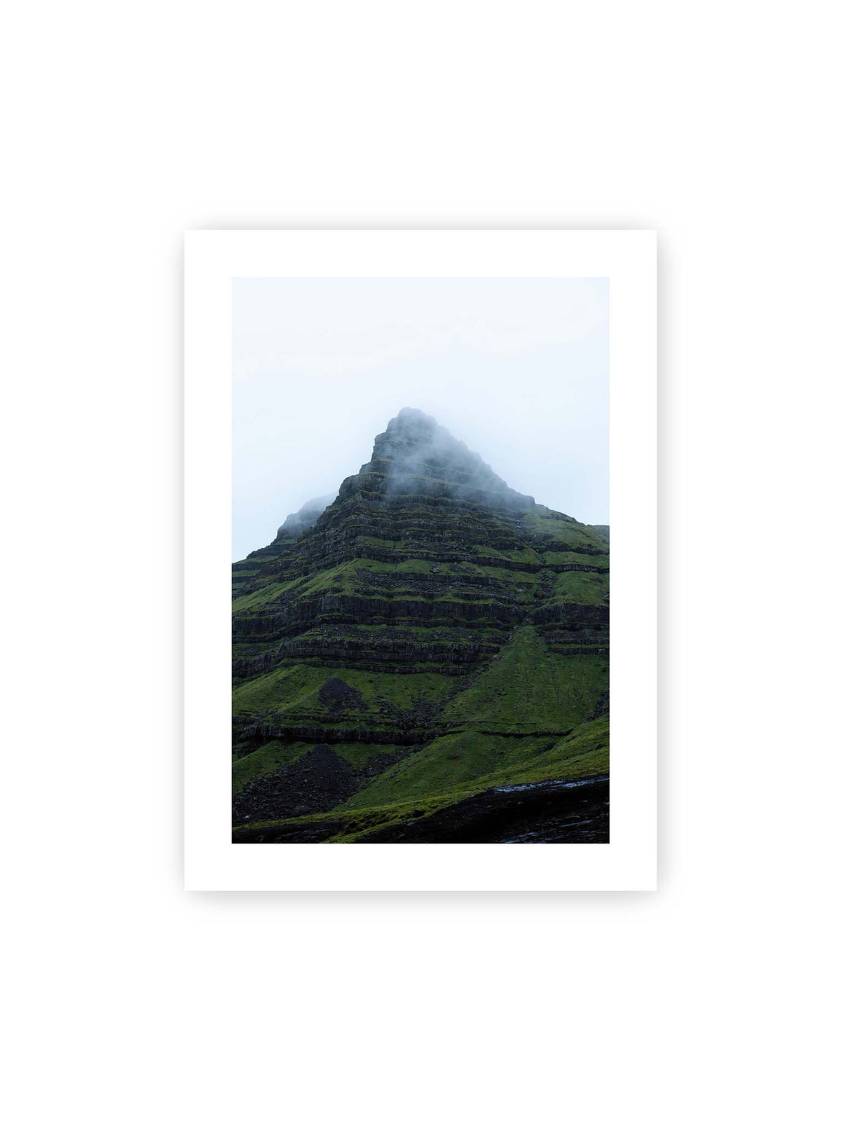 50x70 cm, weißer Galerie-Rand – Steiler grüner Berg mit dunklen Felsbändern, dessen Gipfel in dichtem Nebel verschwindet.