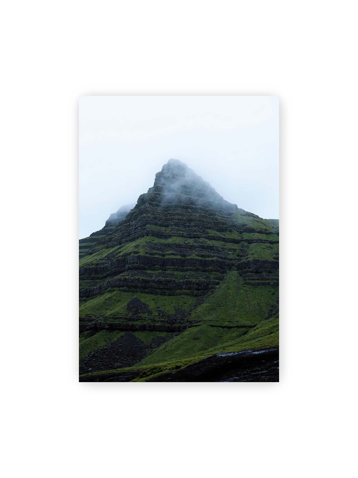70x100 cm – Steiler grüner Berg mit dunklen Felsbändern, dessen Gipfel in dichtem Nebel verschwindet.