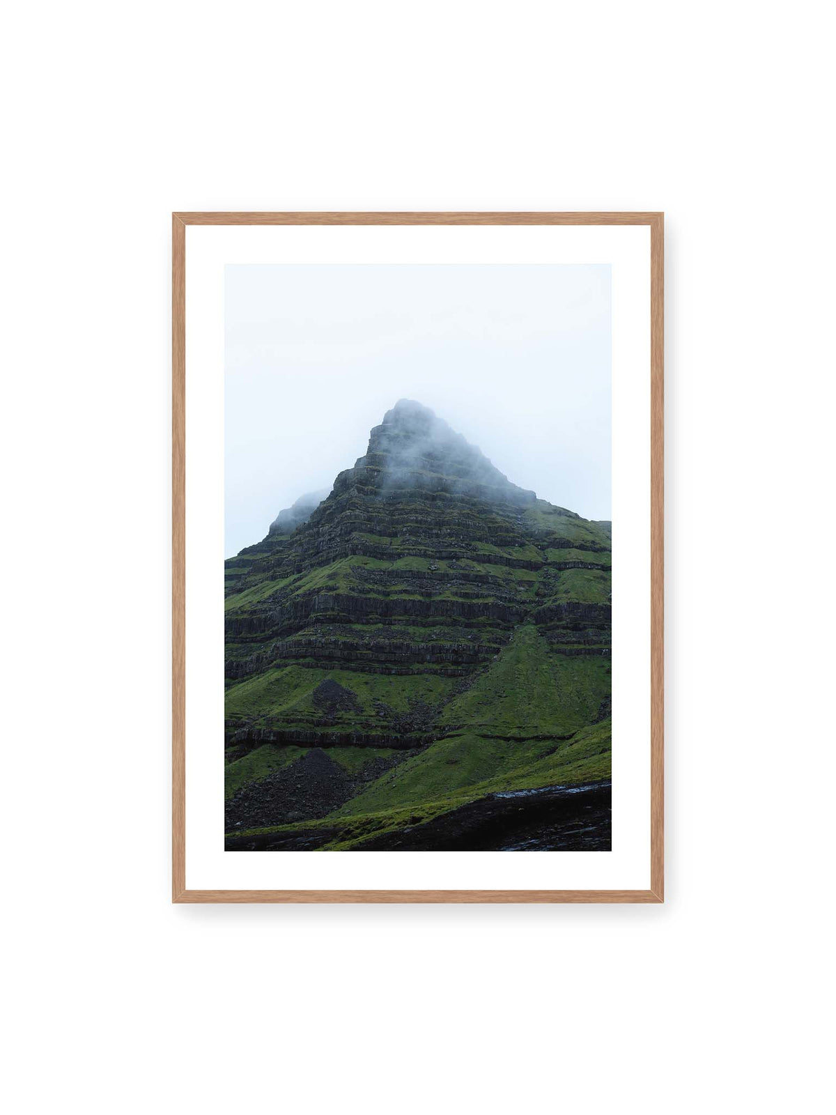 70x100 cm, weißer Galerie-Rand, Eichenrahmen – Steiler grüner Berg mit dunklen Felsbändern, dessen Gipfel in dichtem Nebel verschwindet.