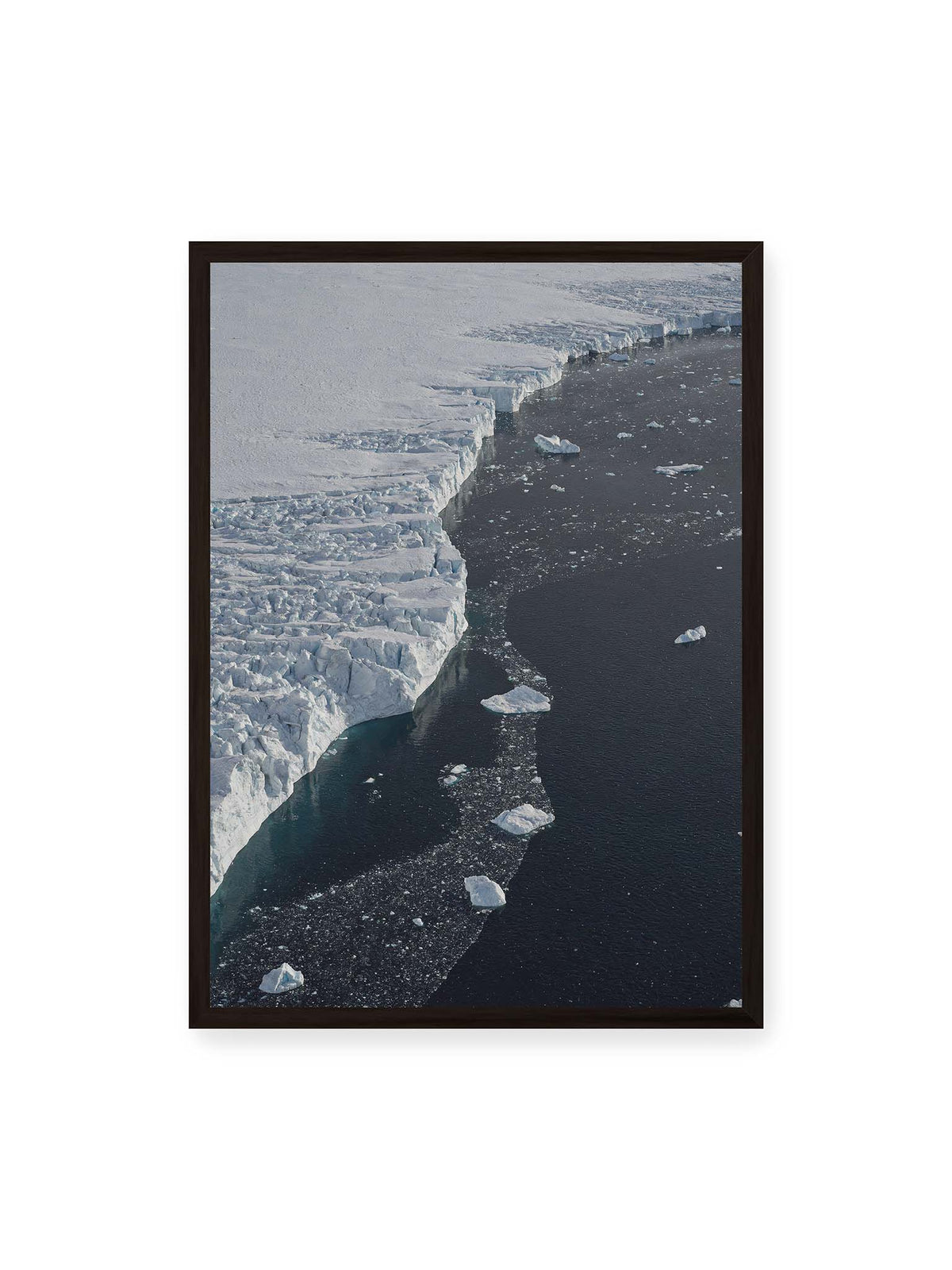 50x70 cm, schwarzer Rahmen – Helle Eisfläche mit geschwungener Kante an dunklem Wasser, auf dem einzelne Eisstücke treiben.