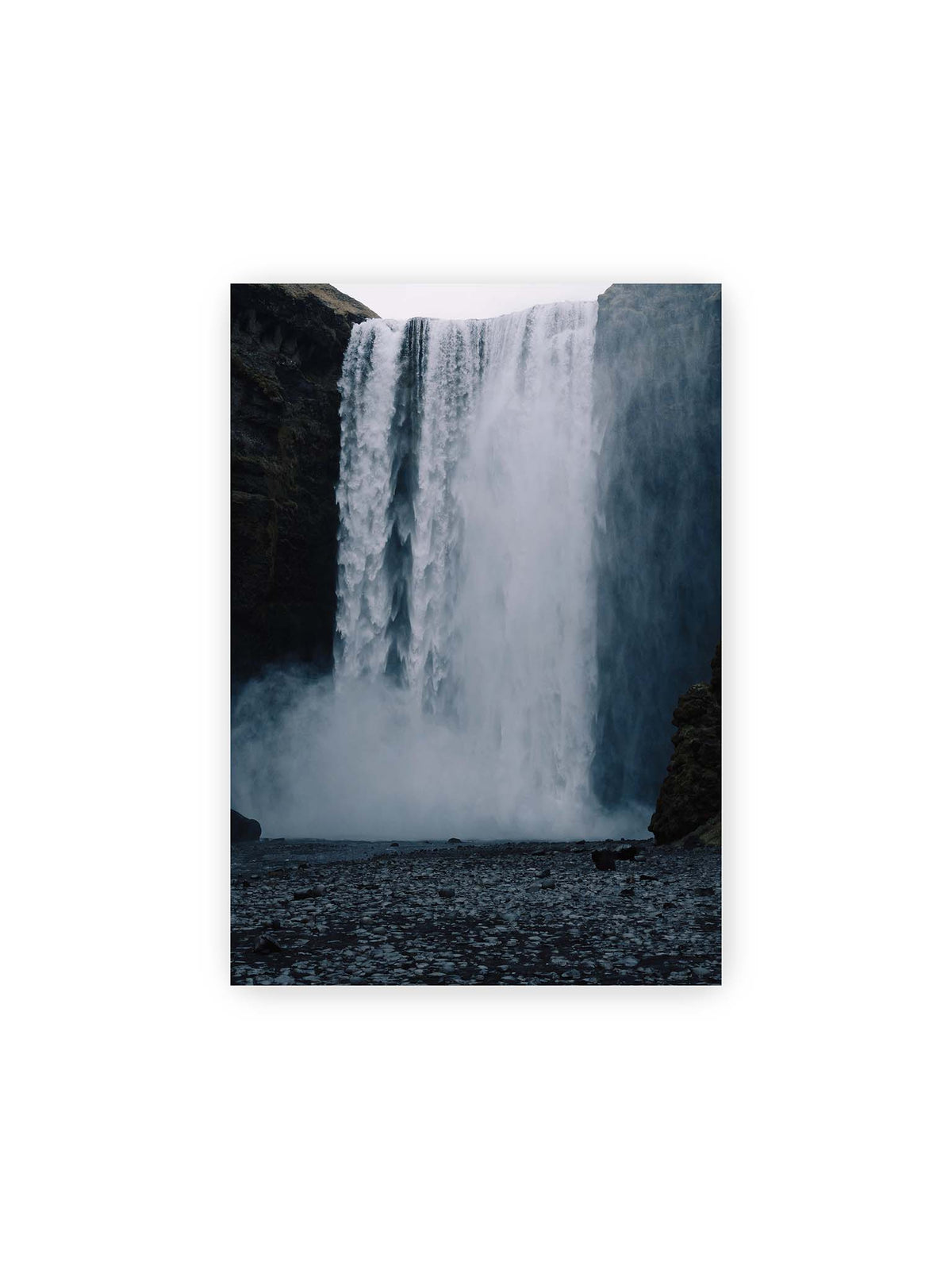 21x30 cm – Mächtiger Wasserfall zwischen dunklen Felswänden mit dichtem Sprühnebel und steinigem Vordergrund.