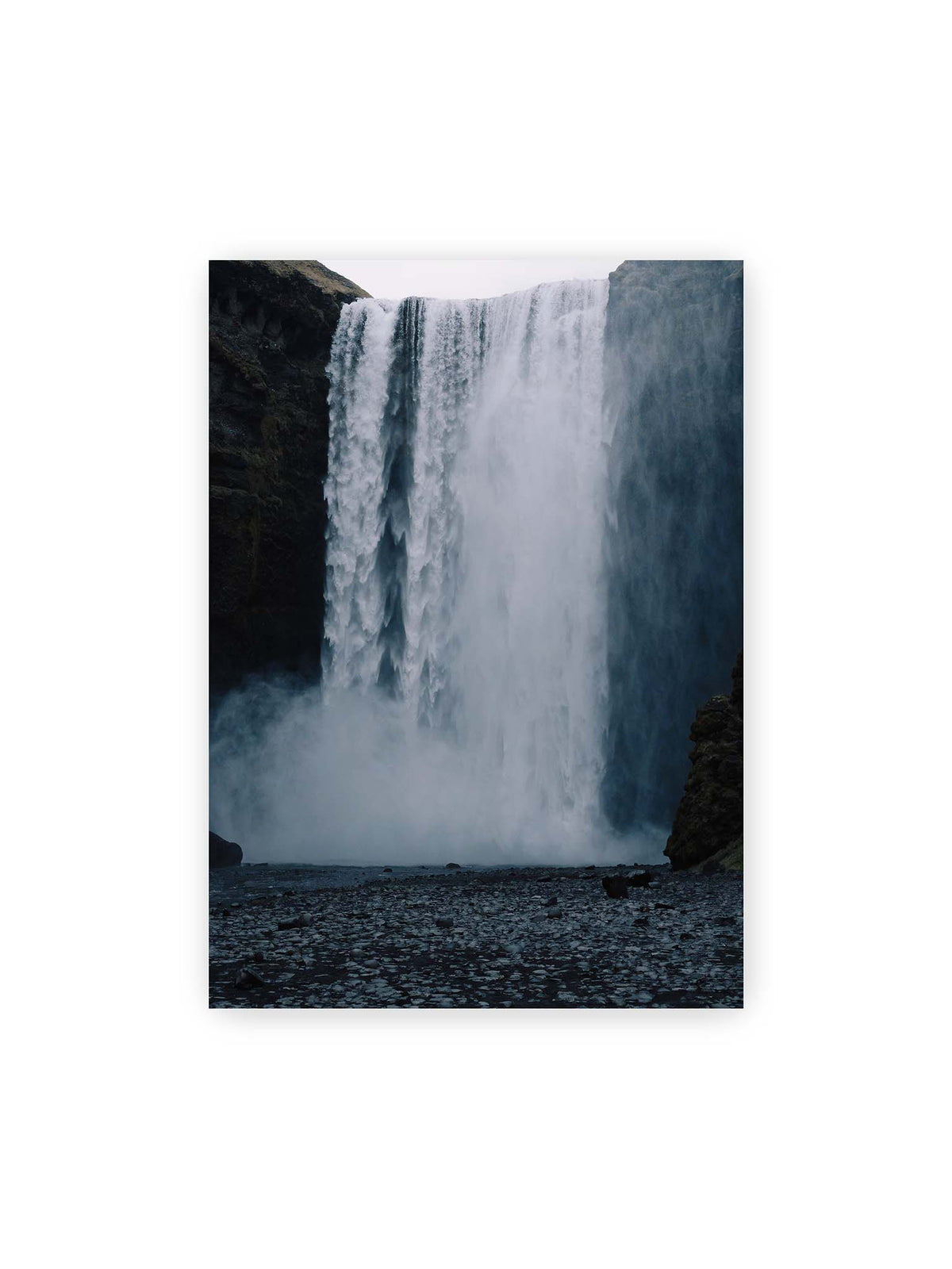50x70 cm – Mächtiger Wasserfall zwischen dunklen Felswänden mit dichtem Sprühnebel und steinigem Vordergrund.