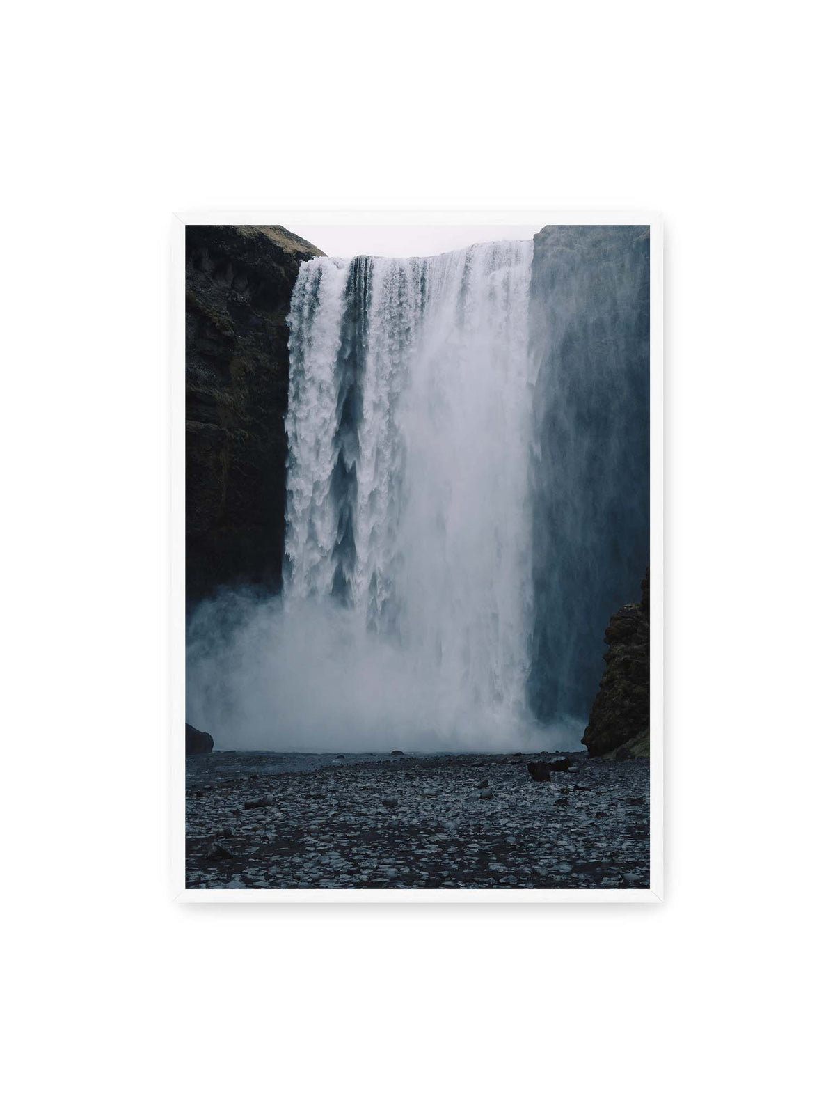70x100 cm, weißer Rahmen – Mächtiger Wasserfall zwischen dunklen Felswänden mit dichtem Sprühnebel und steinigem Vordergrund.