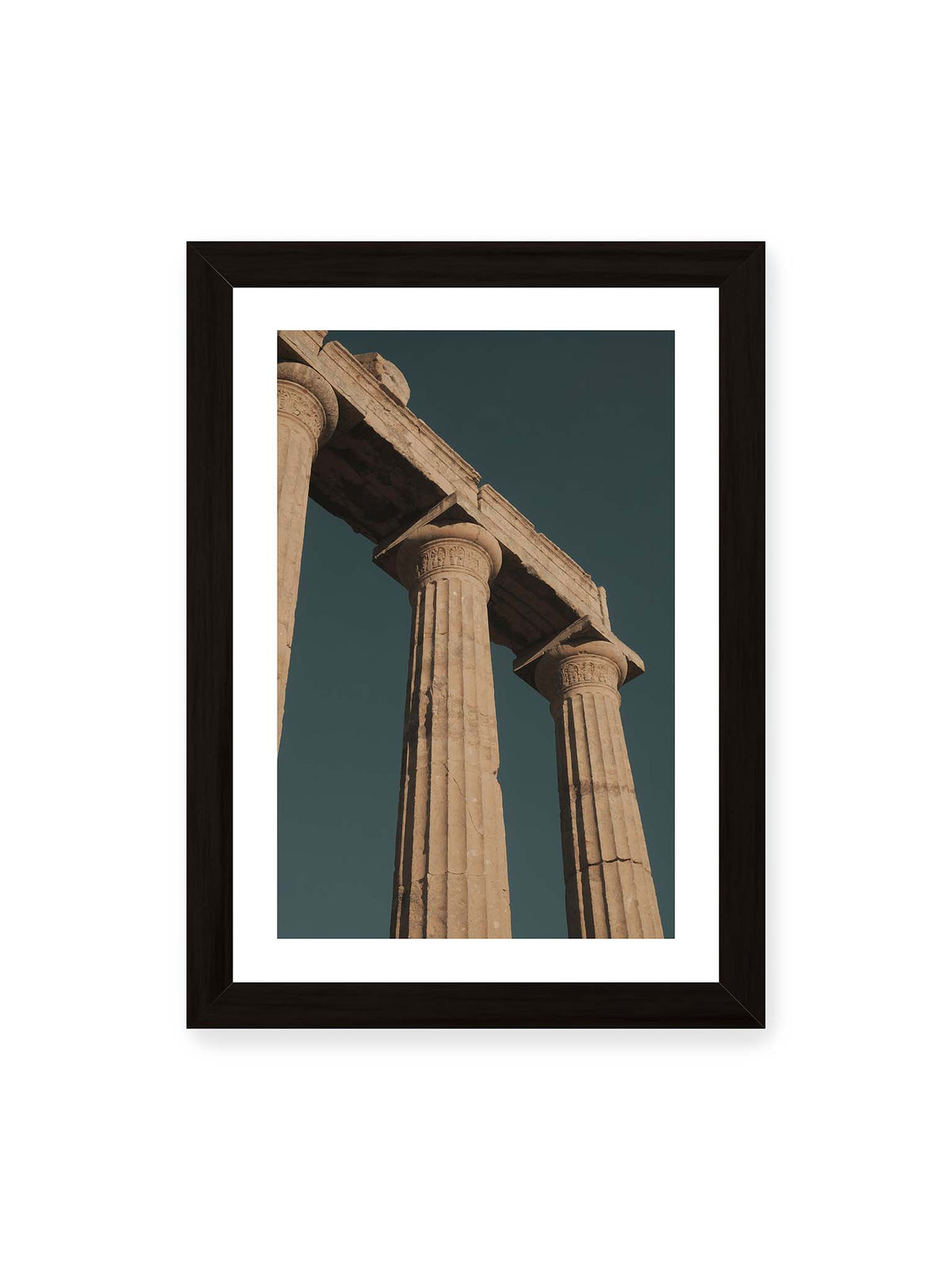 21x30 cm, weißer Galerie-Rand, schwarzer Rahmen – Monumentale Steinsäulen mit verzierten Kapitellen und verwittertem Gebälk vor dunklem Himmel.