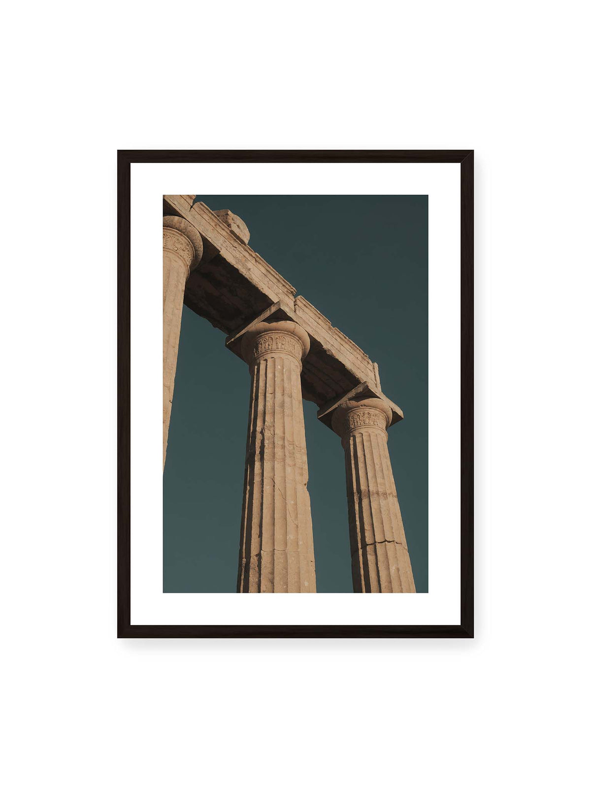 50x70 cm, weißer Galerie-Rand, schwarzer Rahmen – Monumentale Steinsäulen mit verzierten Kapitellen und verwittertem Gebälk vor dunklem Himmel.
