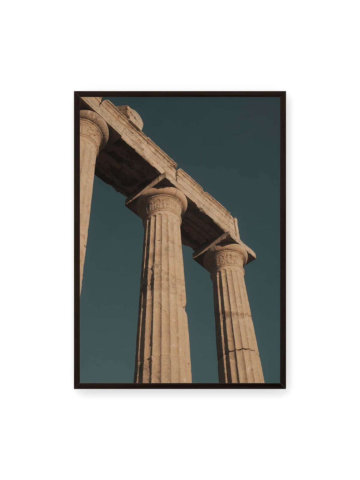 70x100 cm, schwarzer Rahmen – Monumentale Steinsäulen mit verzierten Kapitellen und verwittertem Gebälk vor dunklem Himmel.